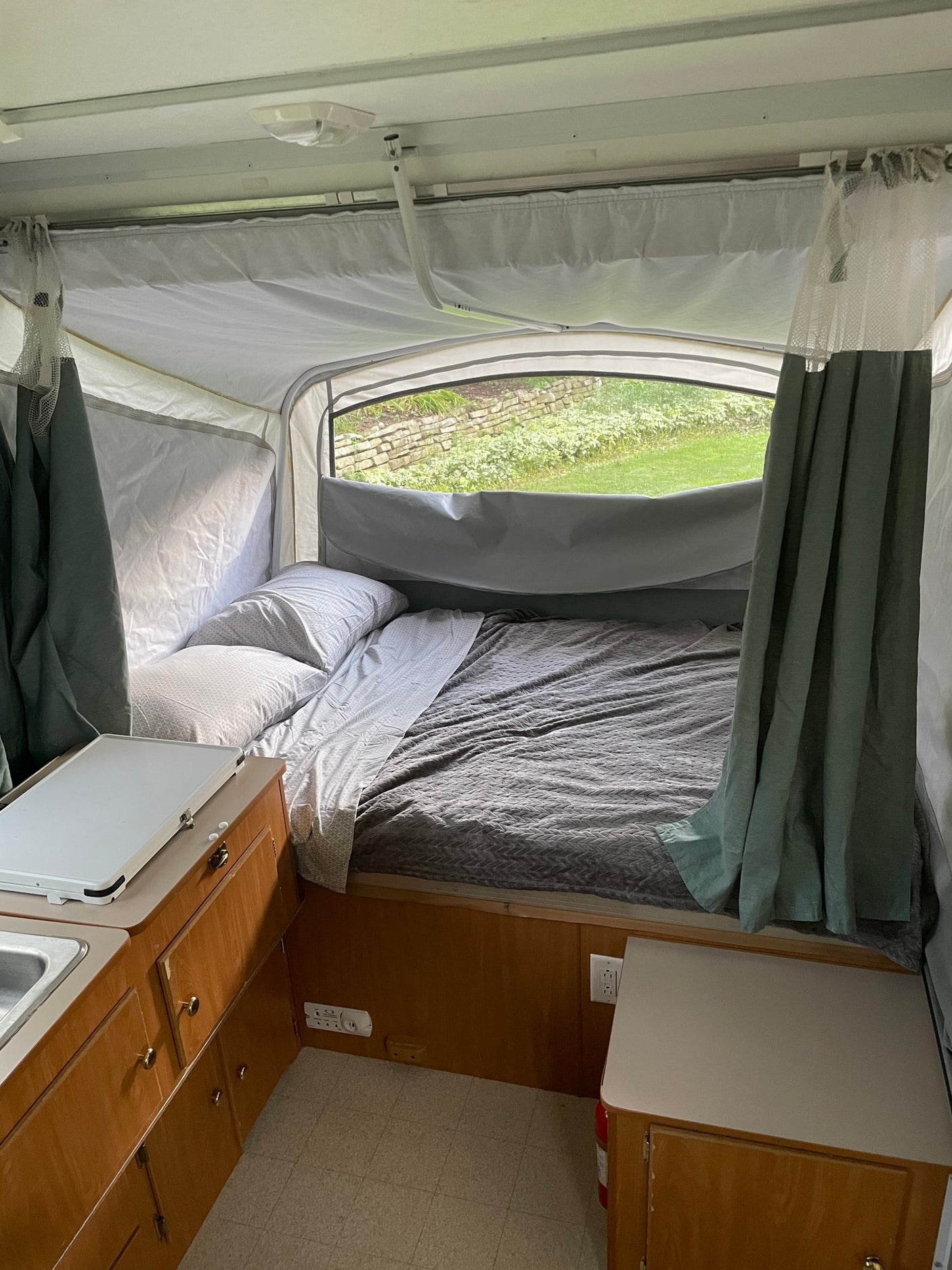 perfect for an RV rental getaway.|Interior of an RV rental pop-up camper featuring a bed with bedding