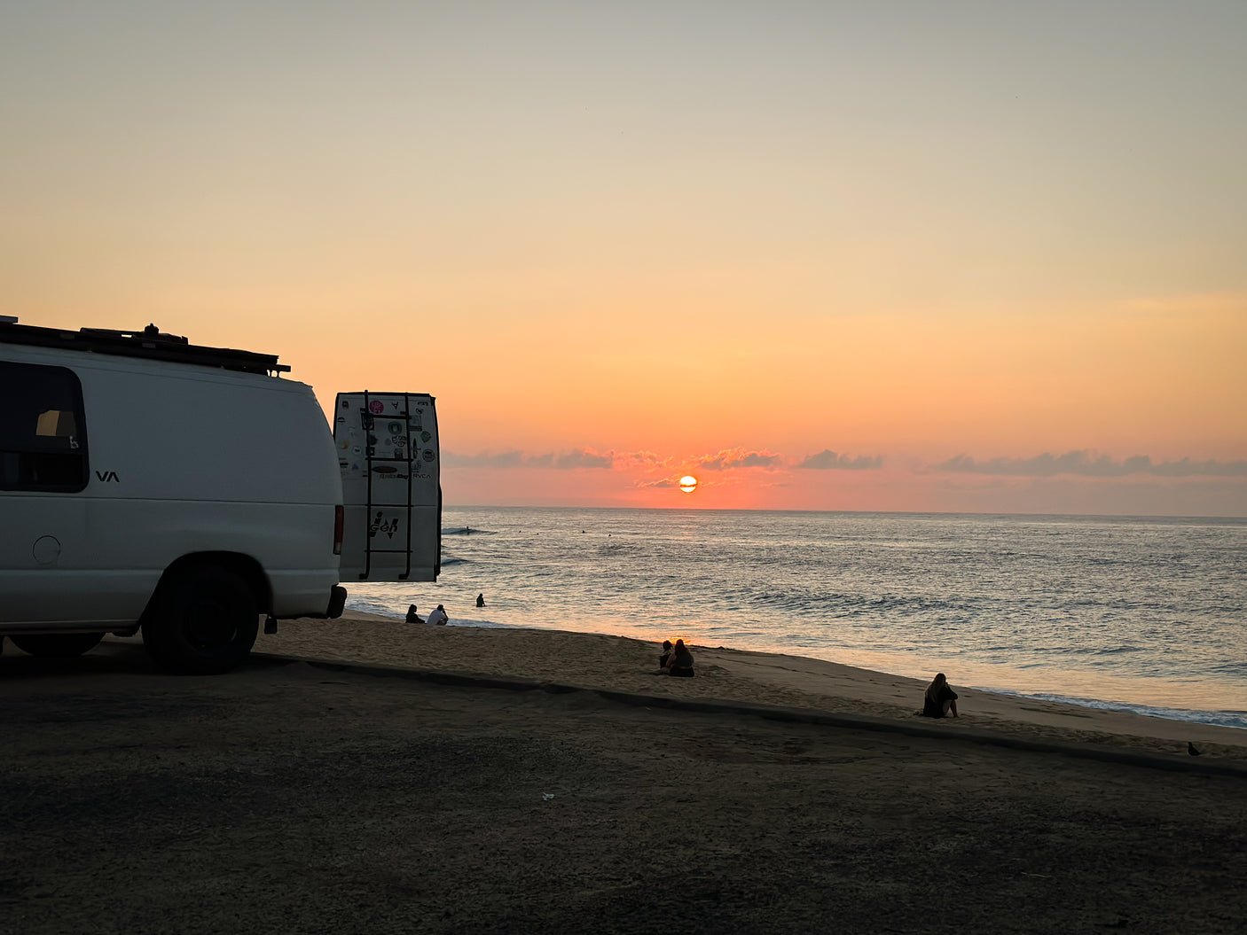 Enjoying a stunning sunset beach view from an RV rental, with people relaxing by the ocean.