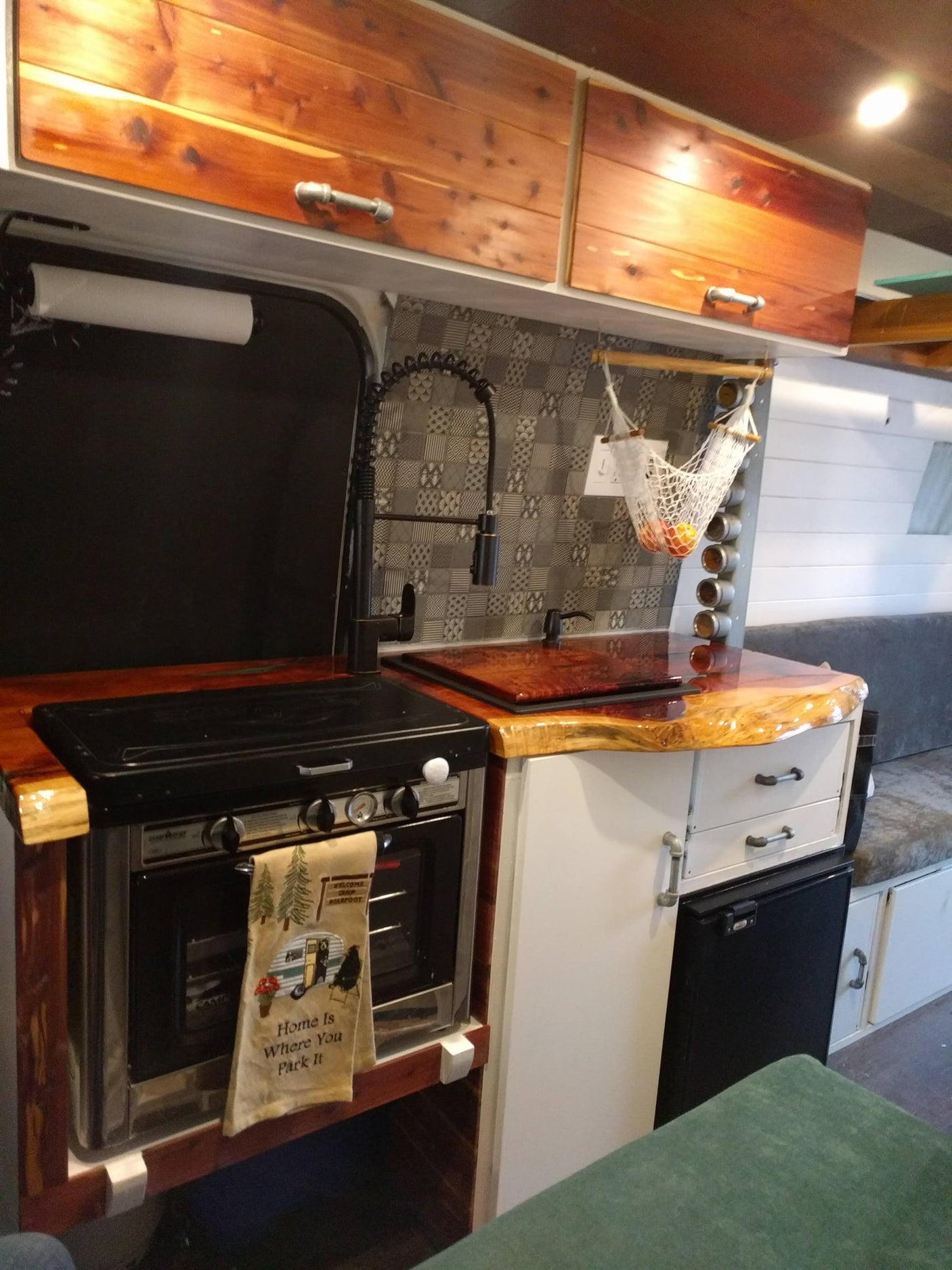 RV rental kitchen interior: cozy camper van with oven, sink, rustic wood countertops, and stylish storage solutions.