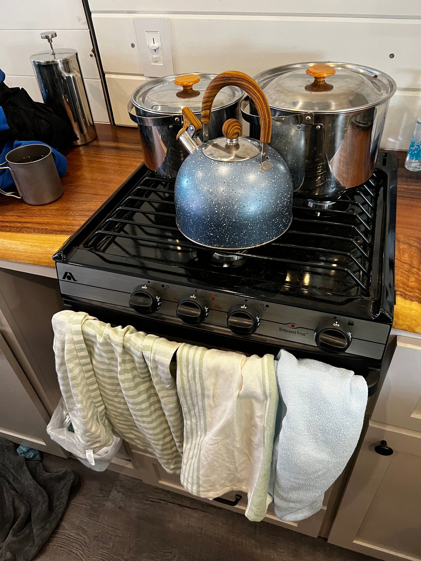 RV rental kitchen: Compact stove with pots, kettle, French press & towels. Ready for cooking! — photo 10
