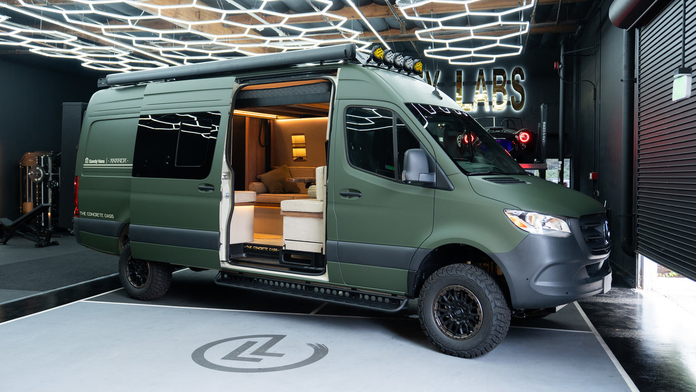Olive green custom Mercedes Sprinter camper van, ideal for rv rental, with open door revealing its luxurious, wood-accented interior.