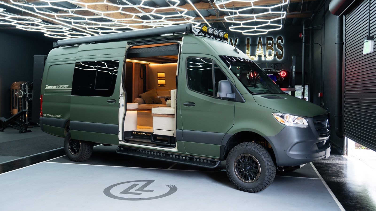 Olive green custom Mercedes Sprinter camper van, ideal for rv rental, with open door revealing its luxurious, wood-accented interior.