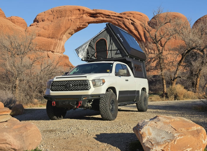 parked under a majestic natural rock arch in the desert.|Overland truck camper interior