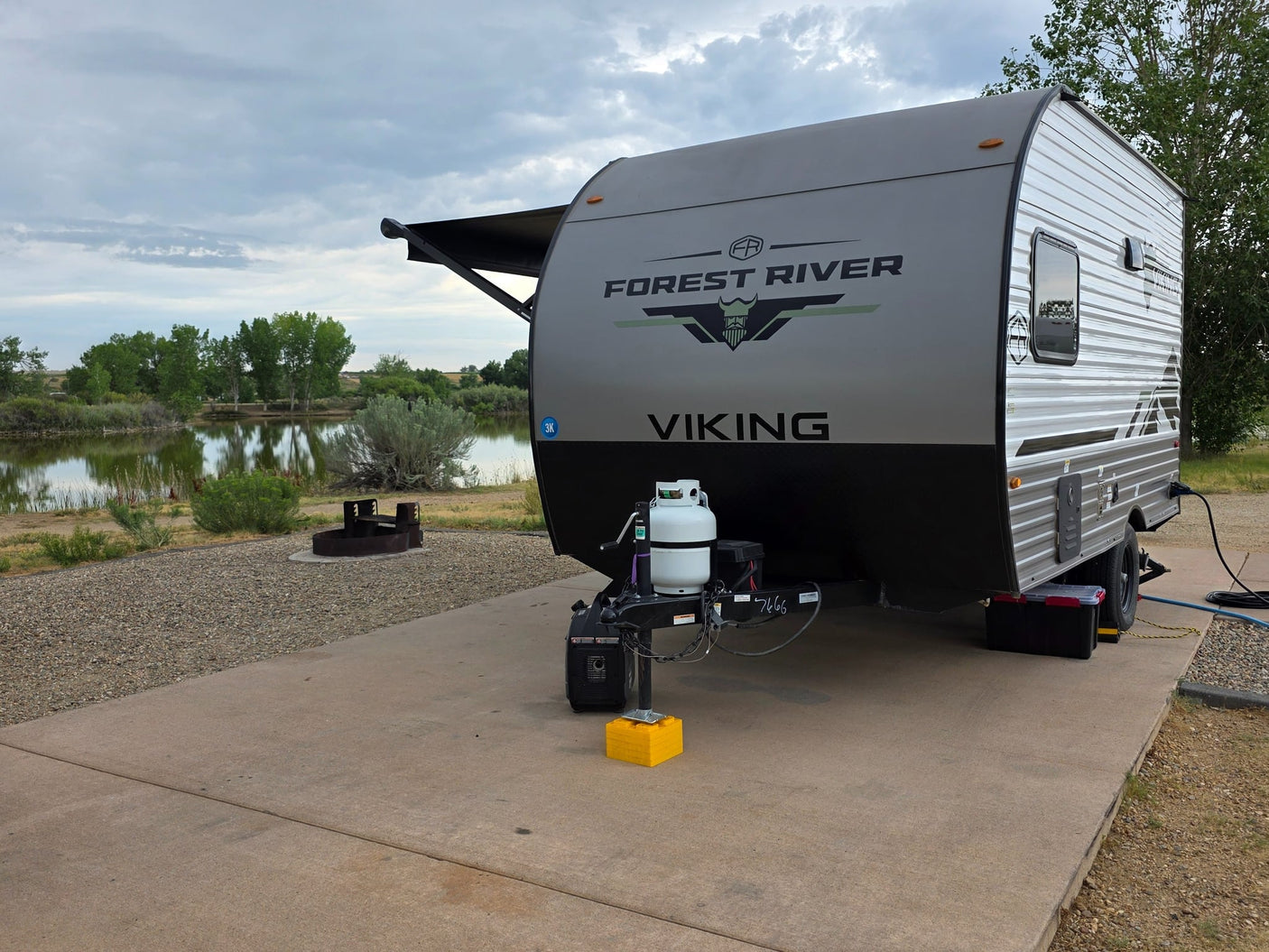 with a fire pit in the foreground.|A Forest River Viking travel trailer