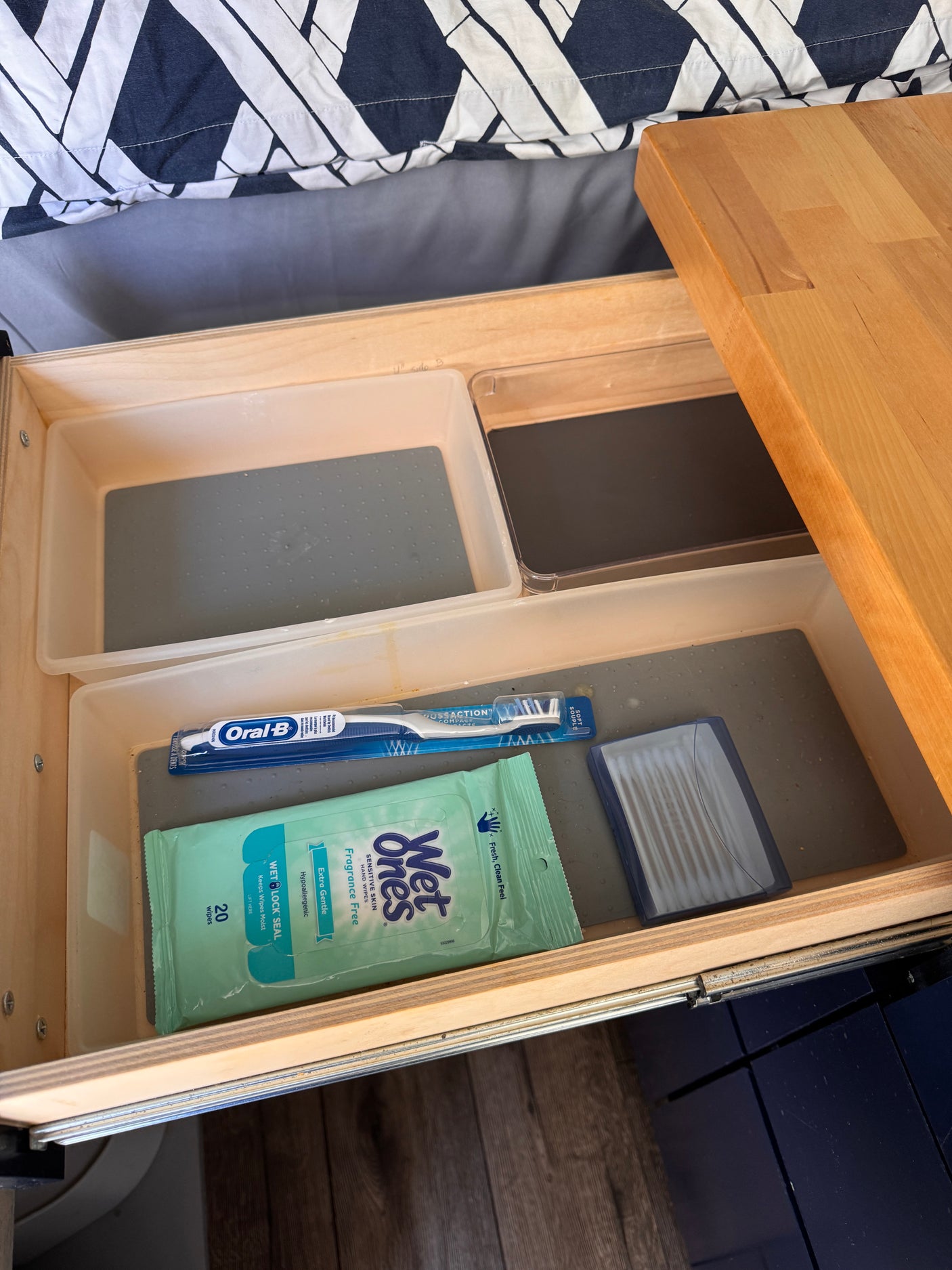 An RV rental's organized drawer: Oral-B toothbrush, Wet Ones wipes, and personal care items on a non-slip liner.