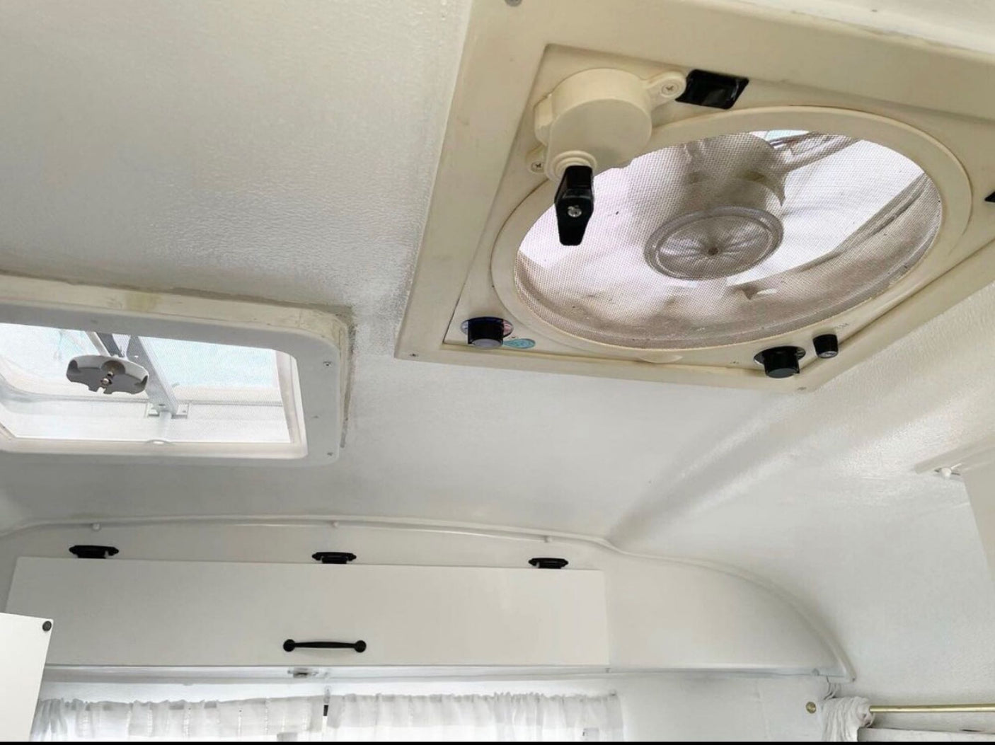 RV rental interior shows a white ceiling with a large fan vent, smaller skylight, and white overhead cabinets.