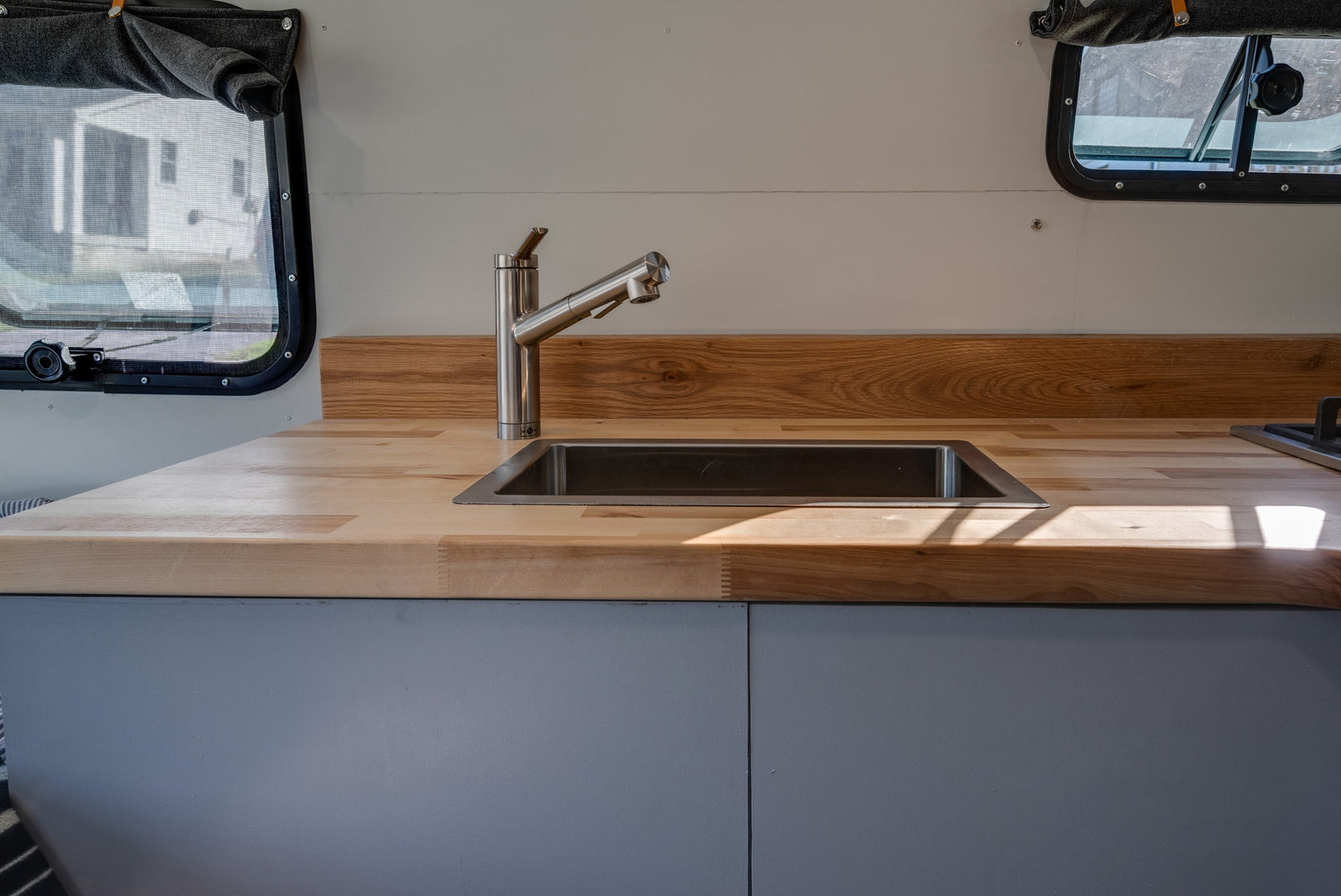 Bright RV rental kitchen with modern stainless steel sink, faucet, and warm wood countertops.