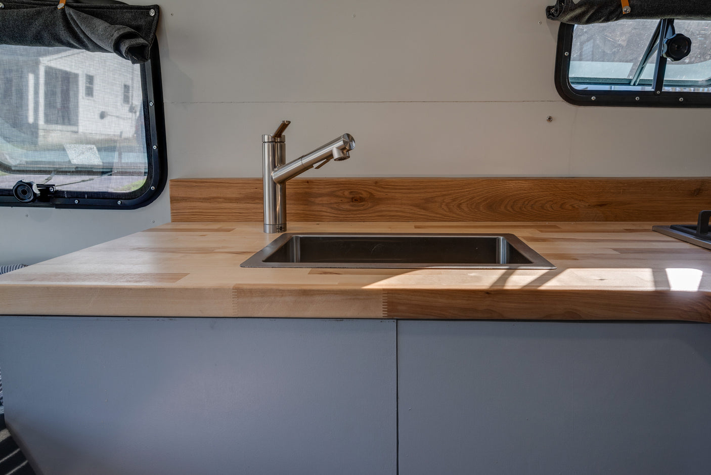 Bright RV rental kitchen with modern stainless steel sink, faucet, and warm wood countertops.