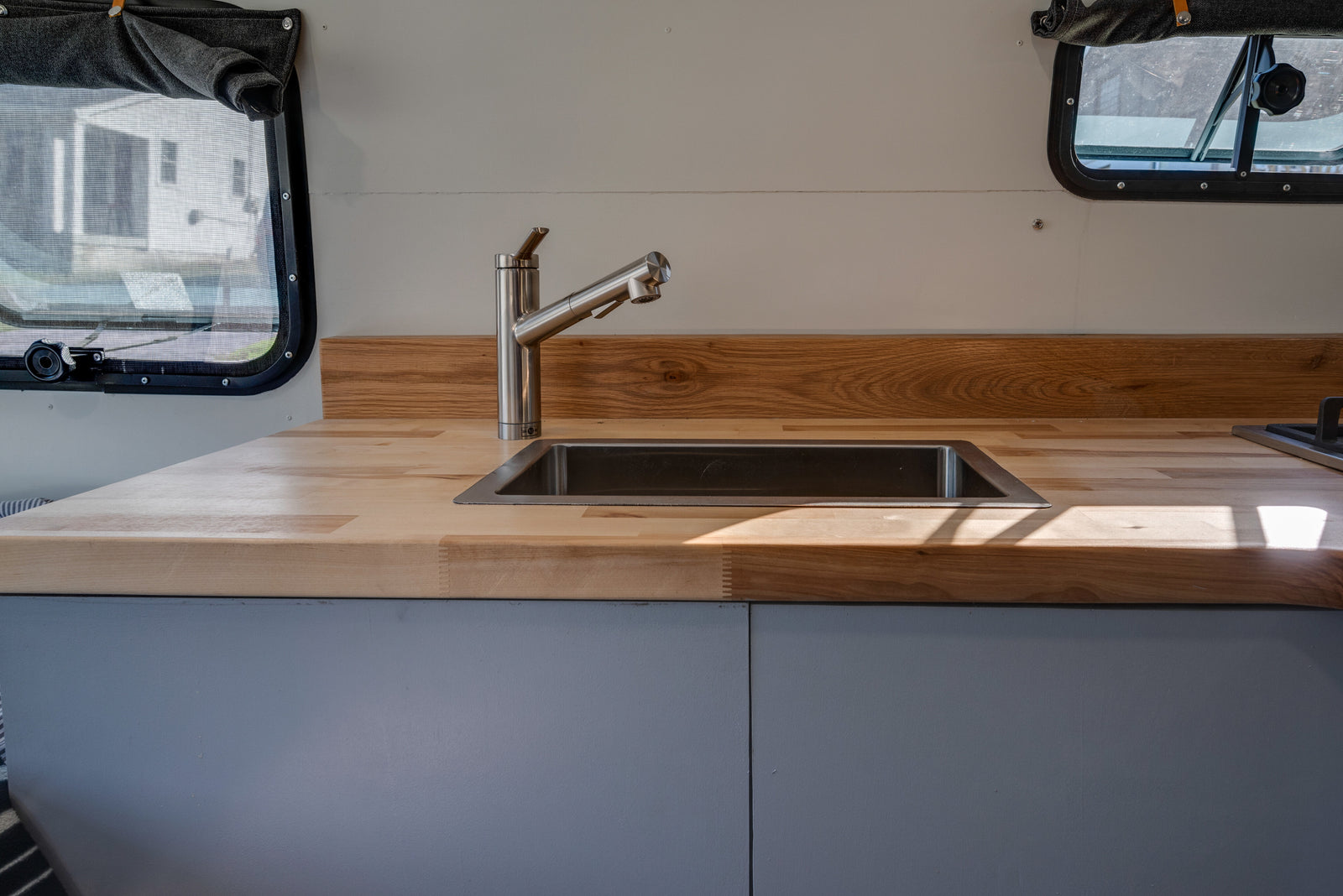 Bright RV rental kitchen with modern stainless steel sink, faucet, and warm wood countertops.