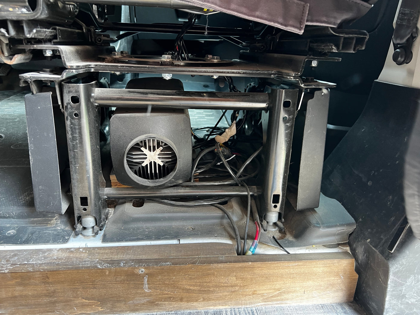 RV rental interior showing a passenger seat base with a fan/heater unit and wiring, a typical camper van modification. — photo 17