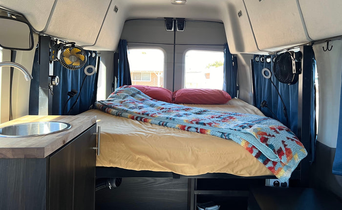 offering a serene water view.|View inside an RV rental: a cozy van interior featuring a comfortable bed
