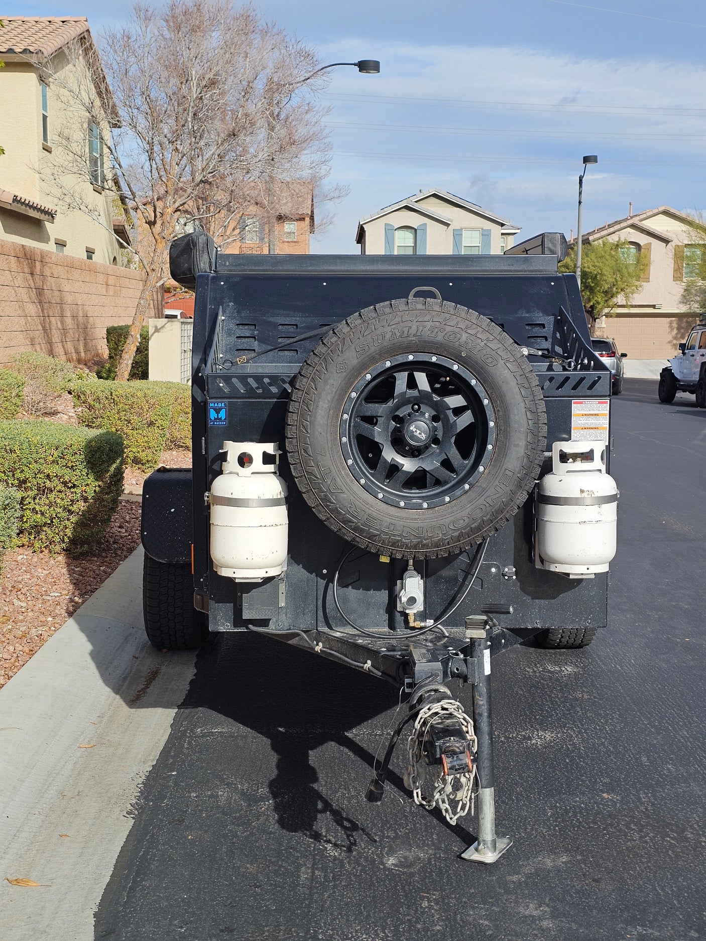 This black off-road trailer, perfect for an rv rental adventure, features a spare tire and propane tanks.