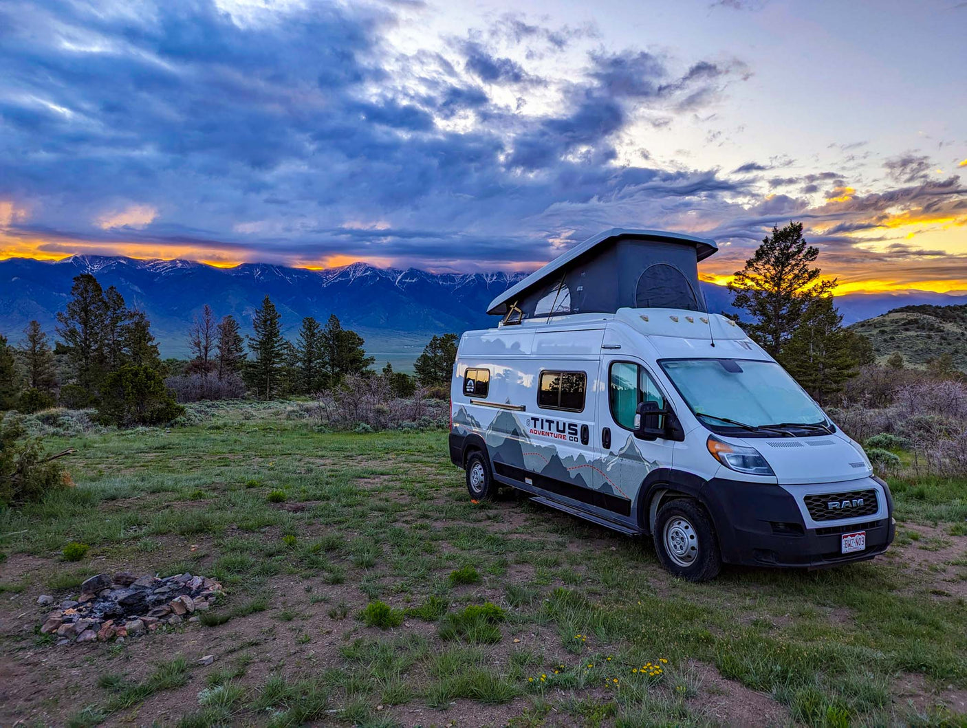 and rugged rock formations through large rear windows.|An RV rental camper van interior featuring an open compact fridge