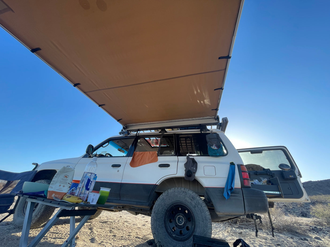 Overlanding SUV with an extended awning, a typical setup for an outdoor adventure or rv rental trip in the desert.