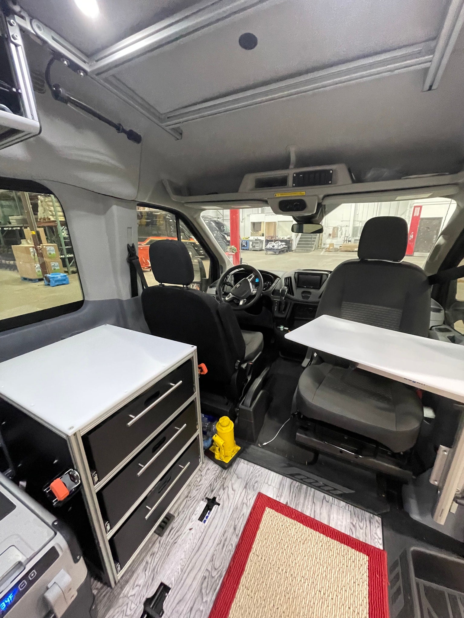 Spacious RV rental camper van interior: front seats, custom storage, and table setup for mobile living.