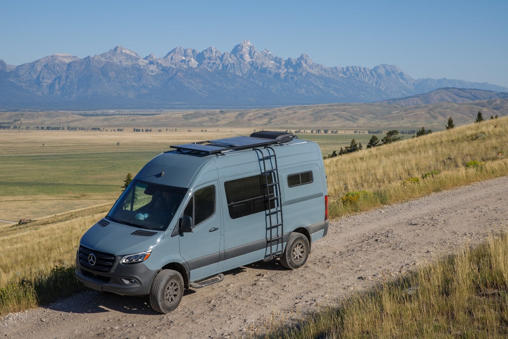 A light blue Mercedes Sprinter camper van on a dirt road — photo 1