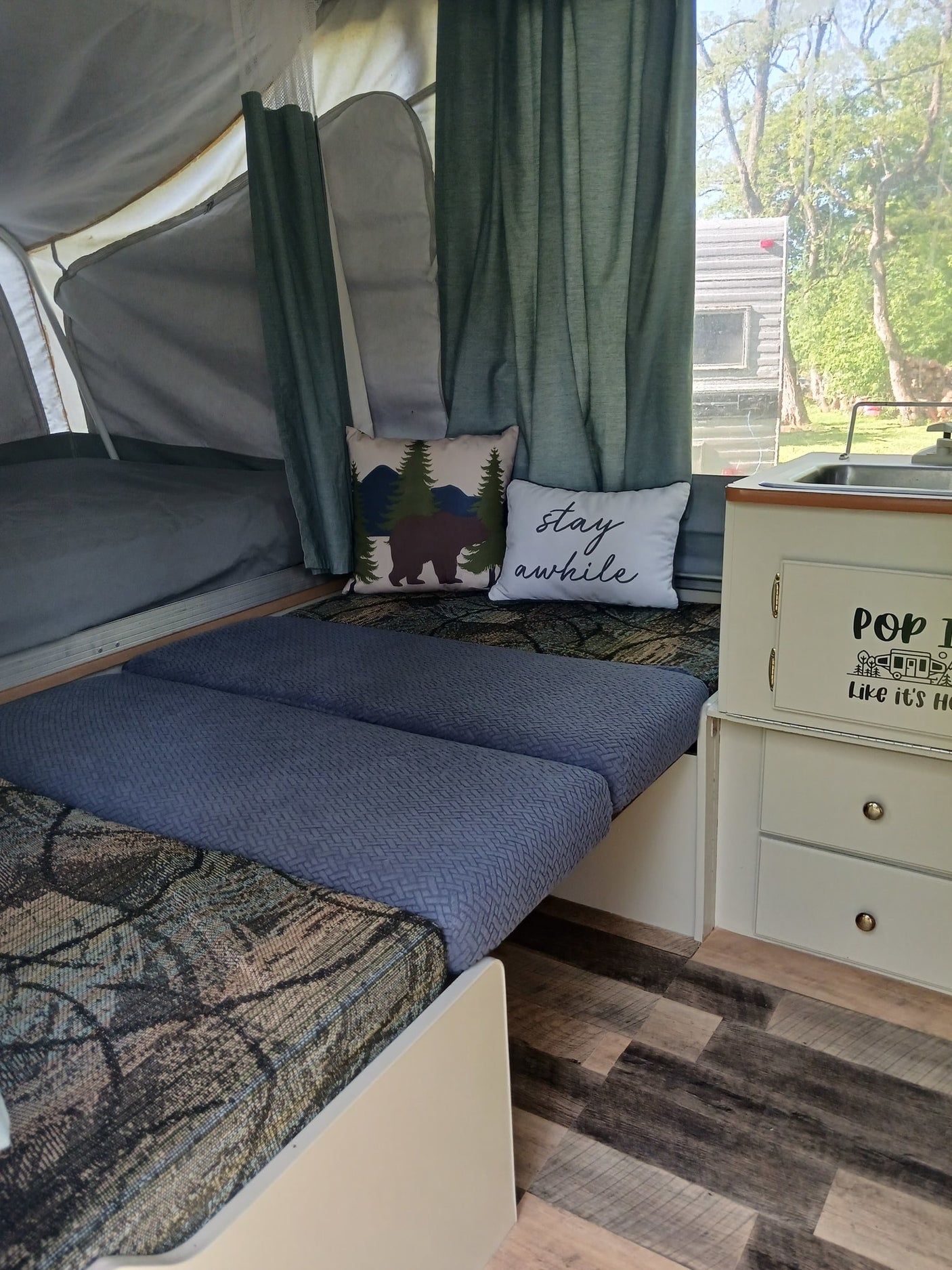 Step into this cozy pop-up camper RV rental, featuring beds with patterned cushions, decorative pillows, and a compact sink area.