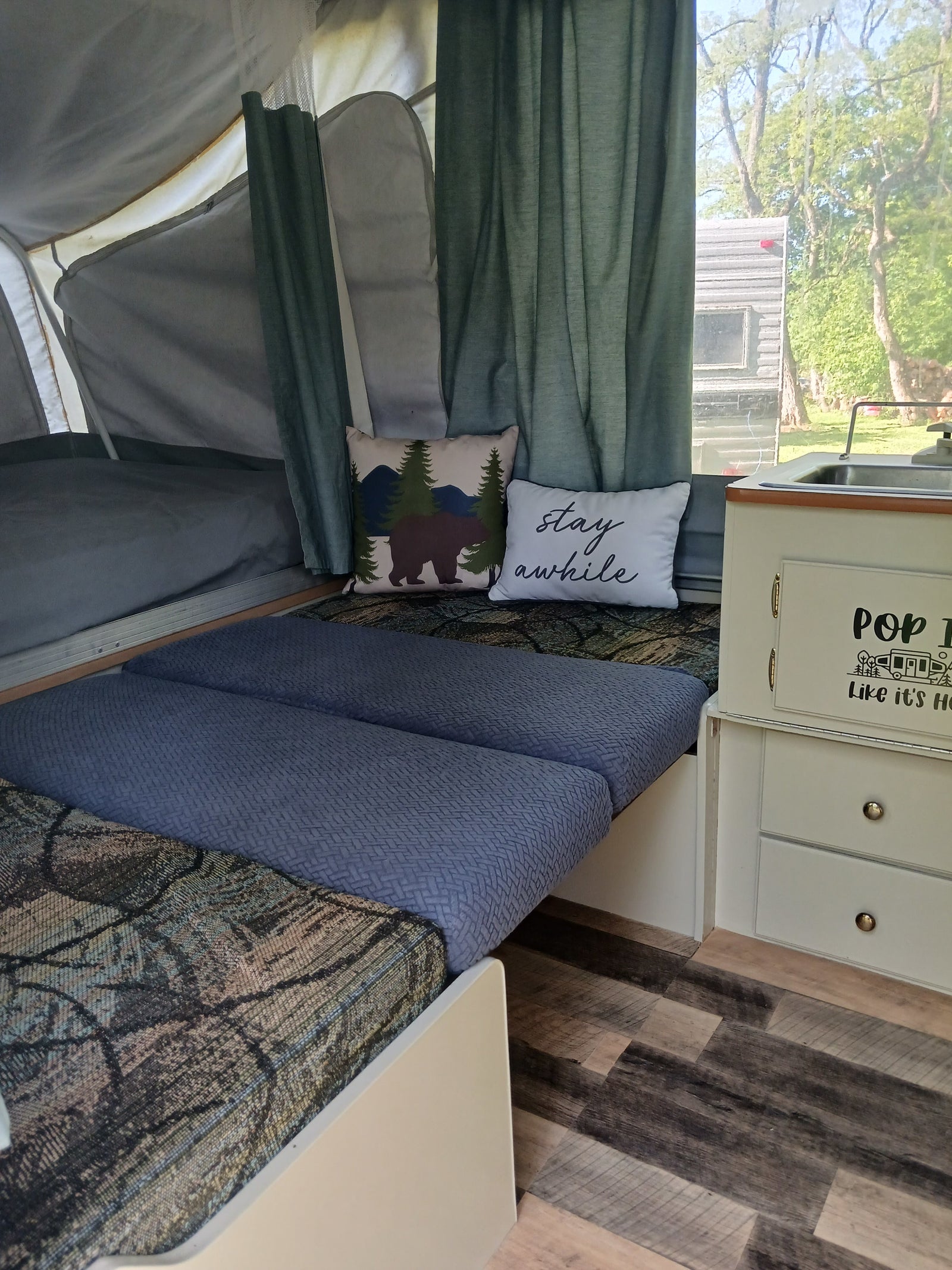 Step into this cozy pop-up camper RV rental, featuring beds with patterned cushions, decorative pillows, and a compact sink area.