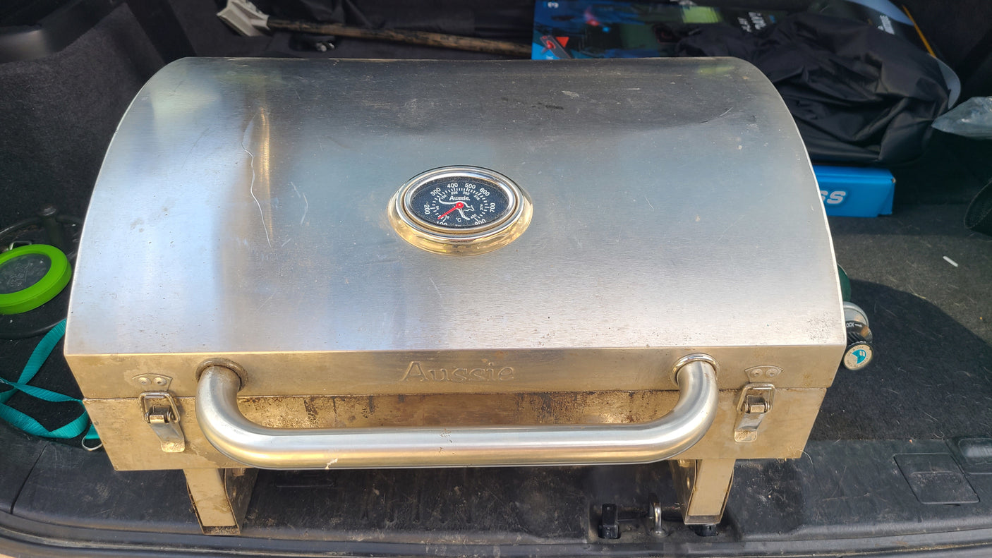 An "Aussie" portable stainless steel BBQ grill in an RV rental trunk, ideal for camping adventures.