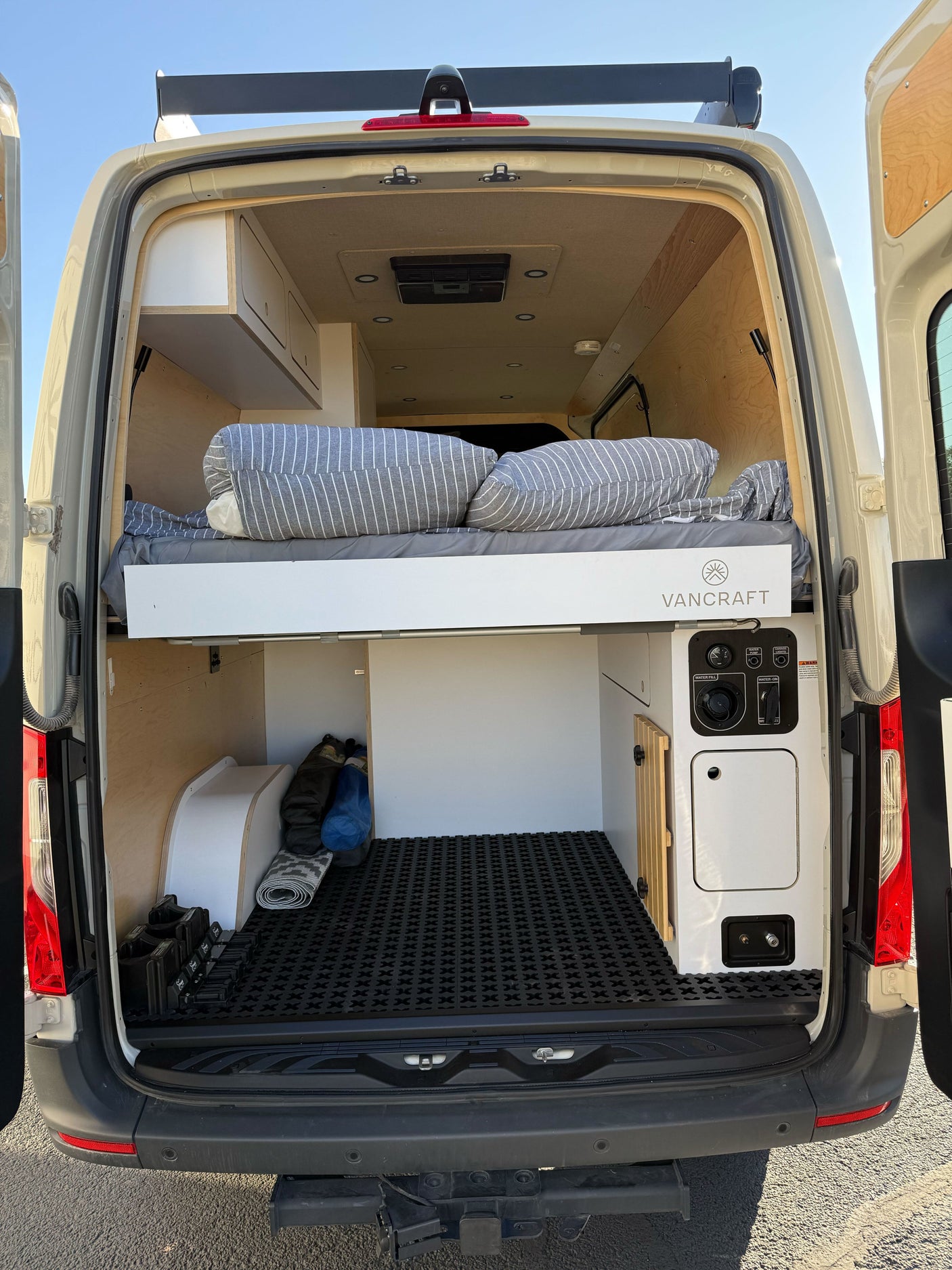 Inside a Vancraft RV rental: rear view with cozy bed, ample storage, and utility controls for your next adventure.