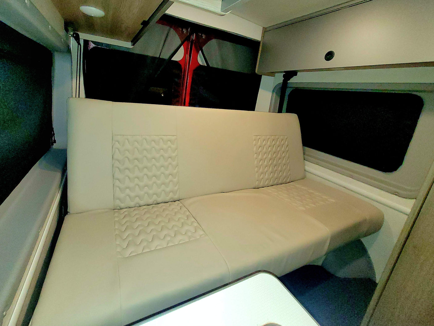 Comfortable RV rental interior with spacious bench seating, overhead storage, and a small table, perfect for travel.