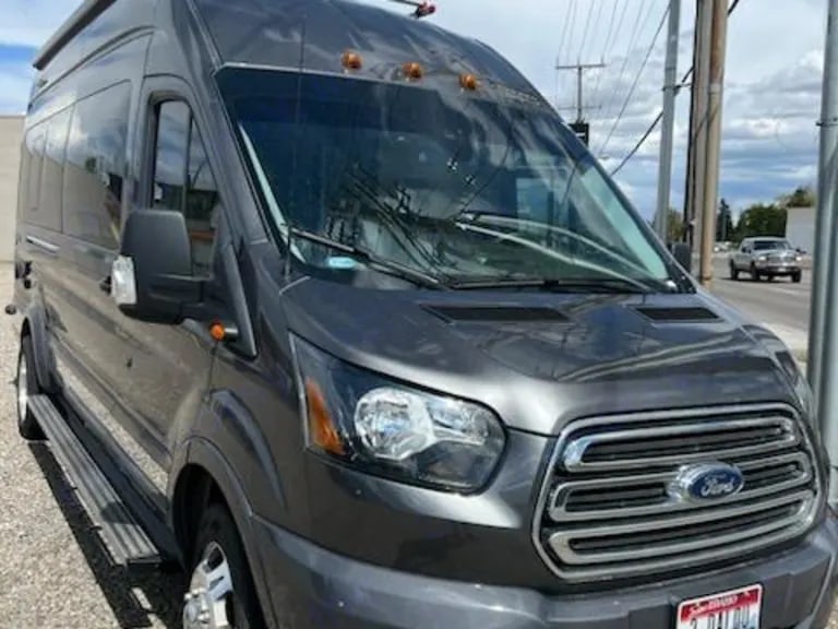 parked next to a textured rock cliff.|Dark gray Ford Transit van