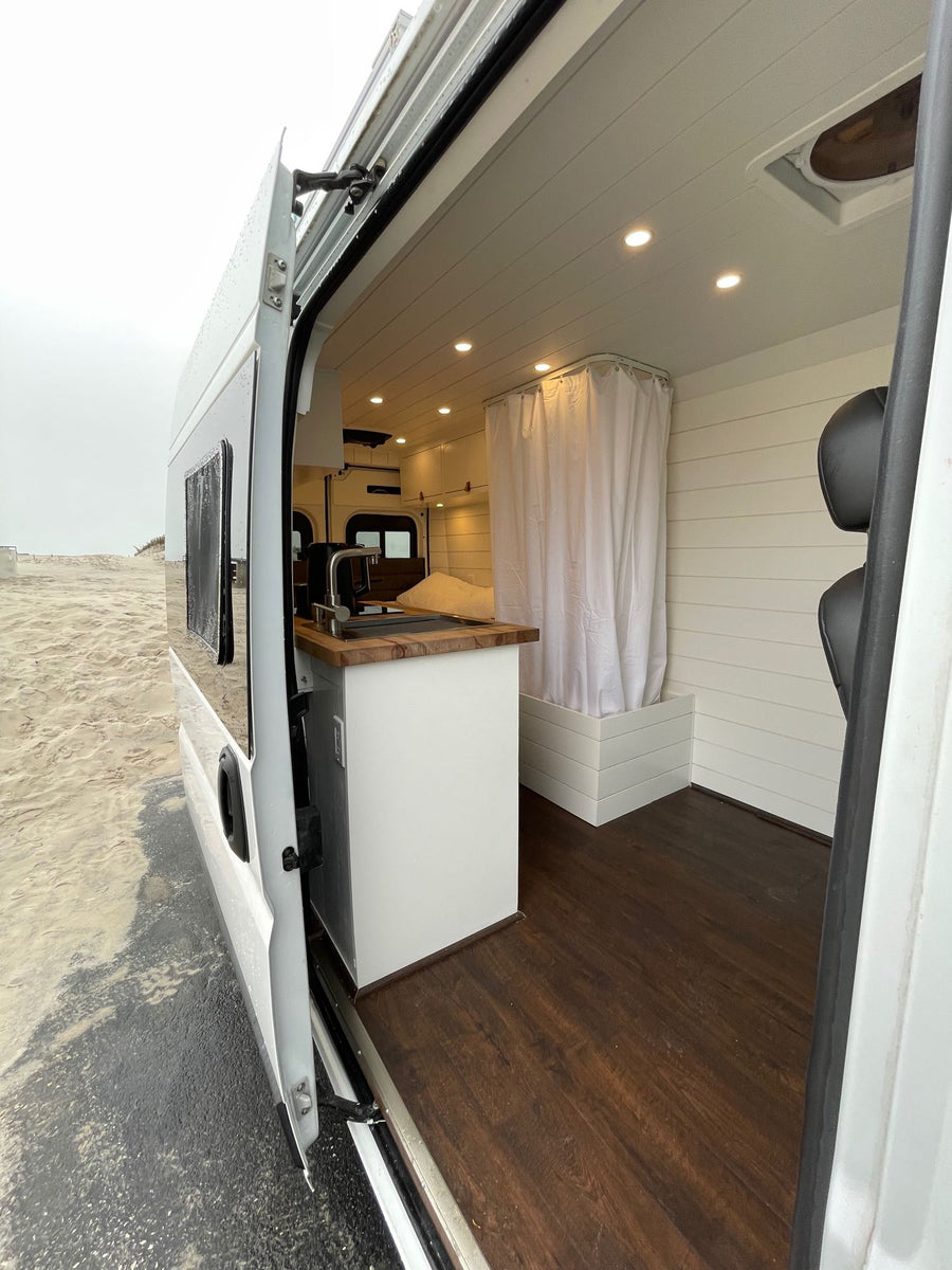 revealing neat interior shelves and a small freezer for convenience.|RV rental under-sink cabinet: Shows grey water tank