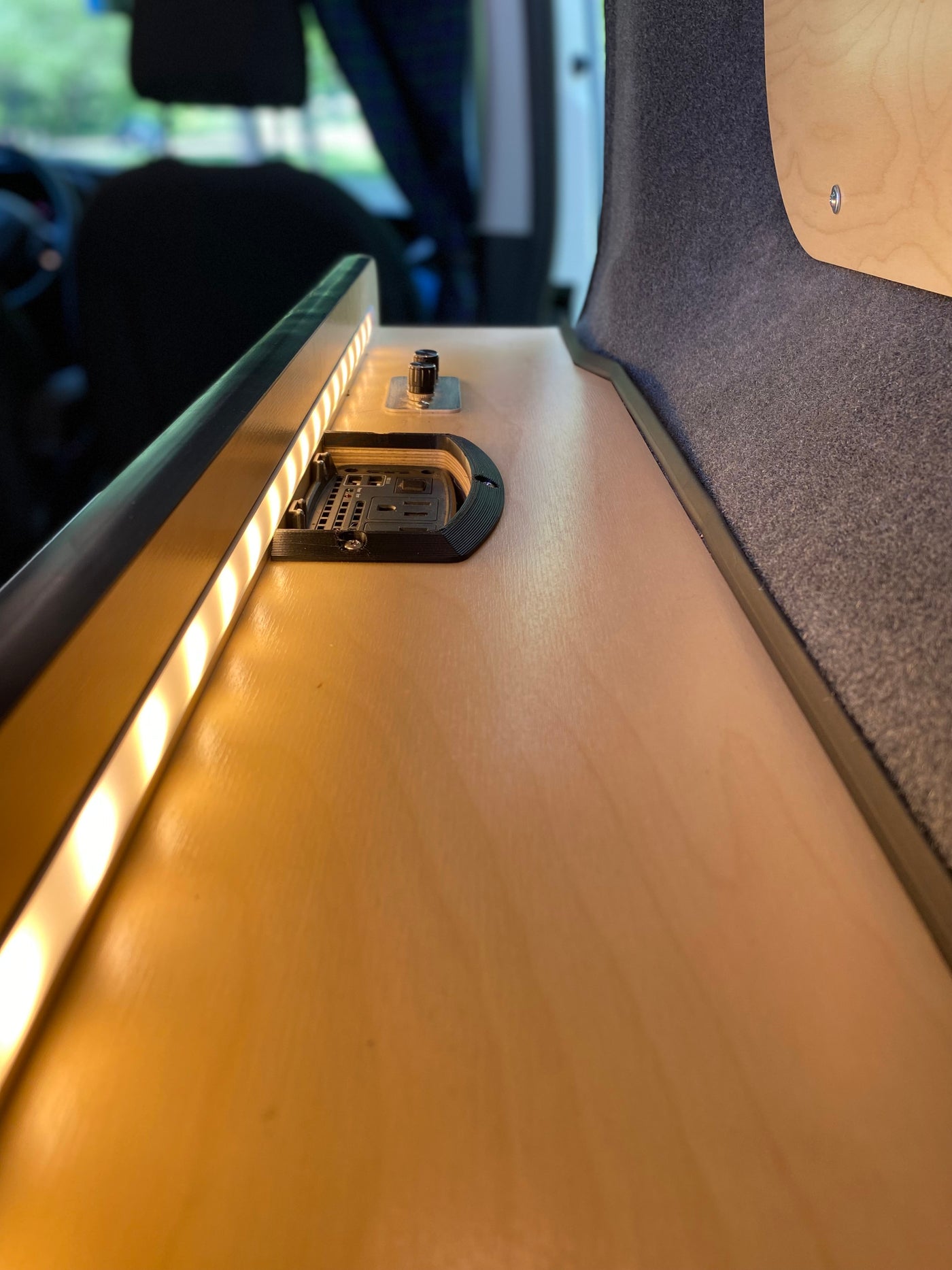 RV rental comfort: illuminated wood counter with LED lights, power outlets & controls. Plush wall fabric adds warmth. — photo 15