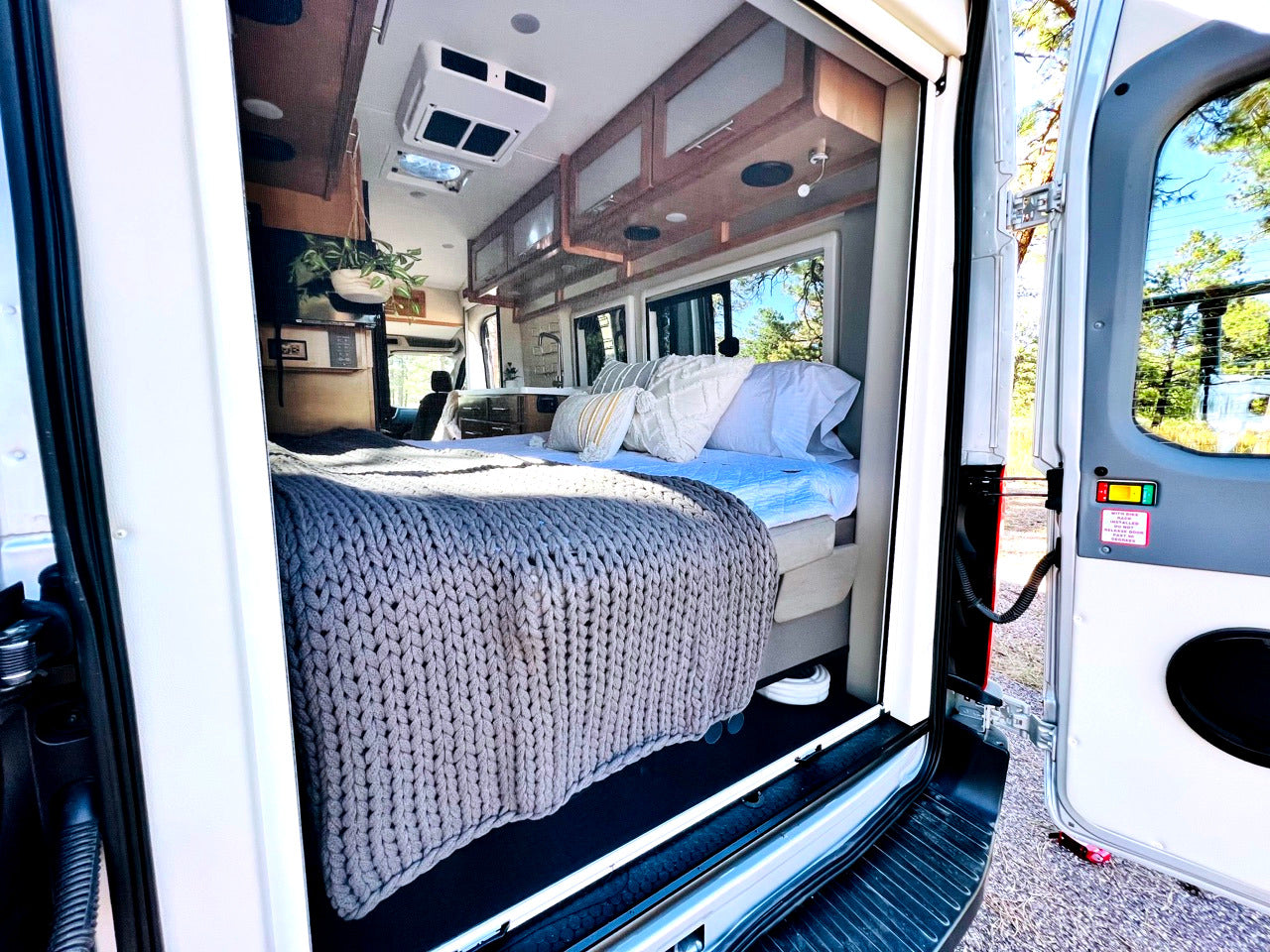 Explore a modern RV rental! This cozy camper van interior features a comfy bed and sleek design for your next adventure.