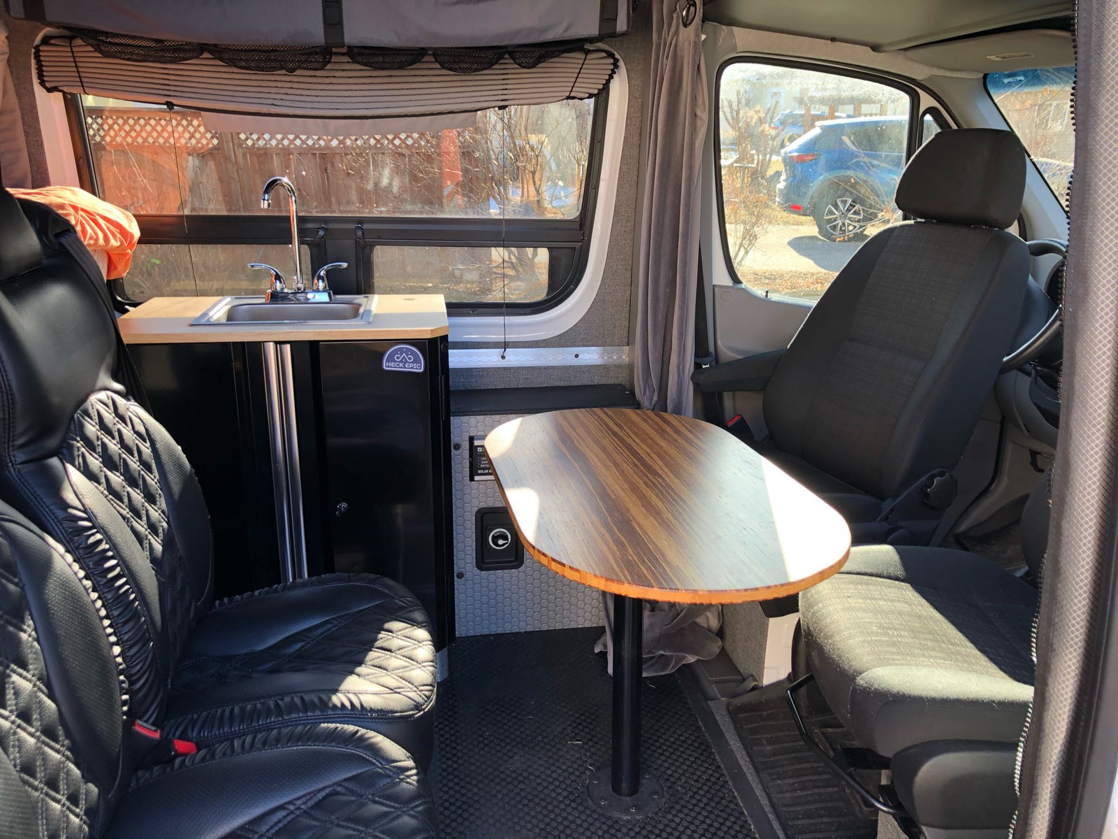 RV rental interior: modern camper van with compact kitchenette, dining table, and comfortable seating, ideal for road trips.