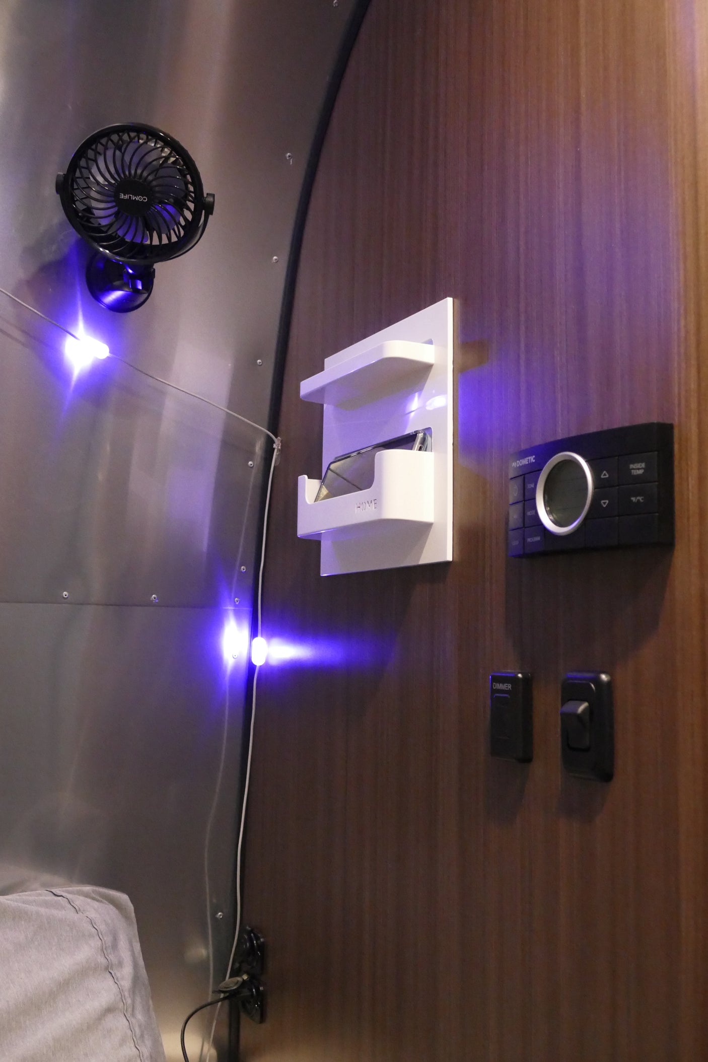 RV rental interior: Fan, HOME organizer, and Dometic climate control panel on wood/silver walls with blue LED lighting.