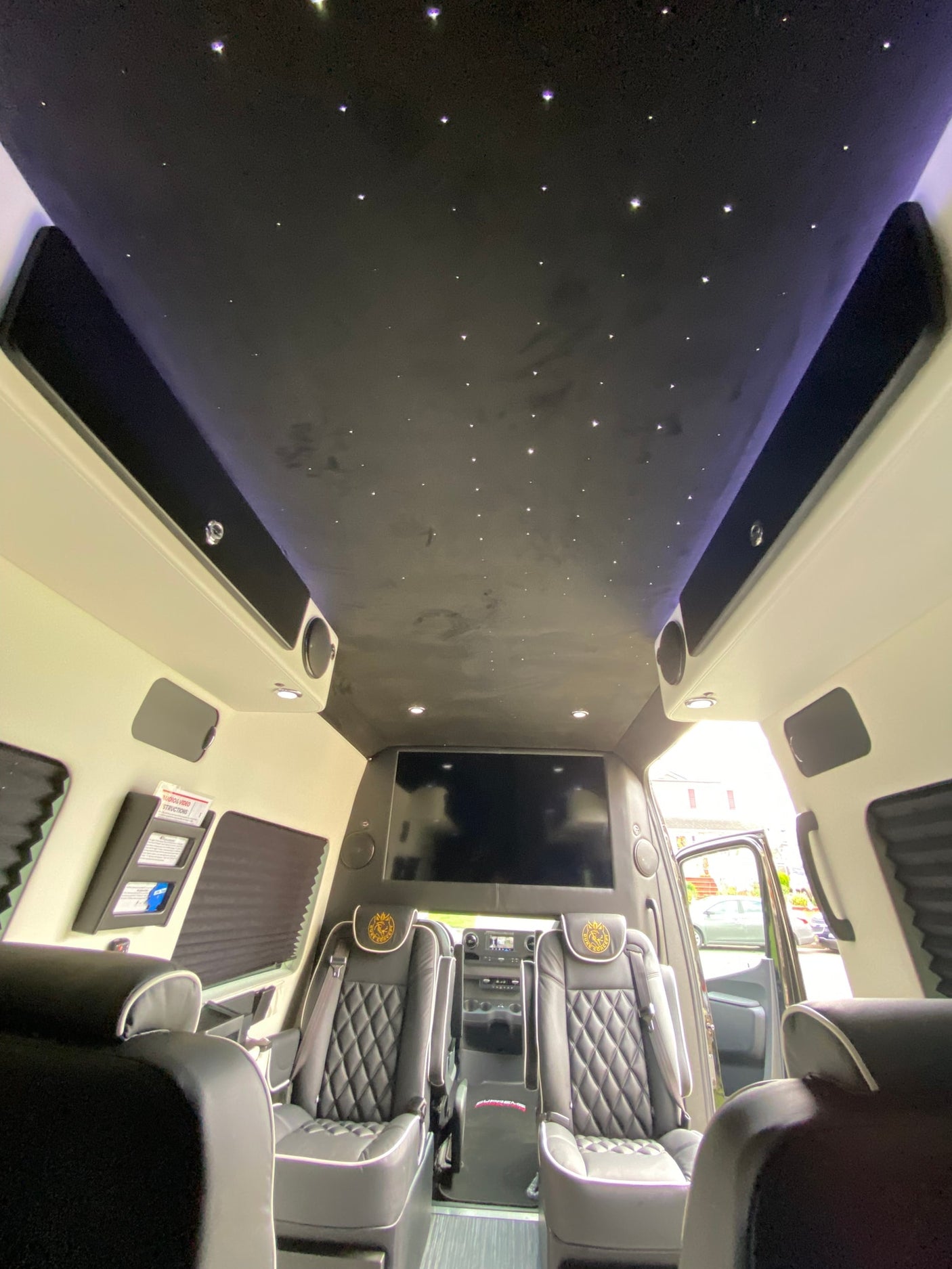 Step inside this luxury RV rental: a plush interior with a starlight ceiling, large TV, and custom seats await your journey.