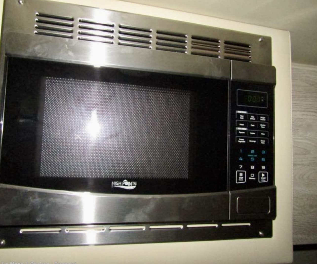 Shiny stainless steel microwave with a black door & digital clock (0:00), built into an RV rental kitchen cabinet. — photo 7