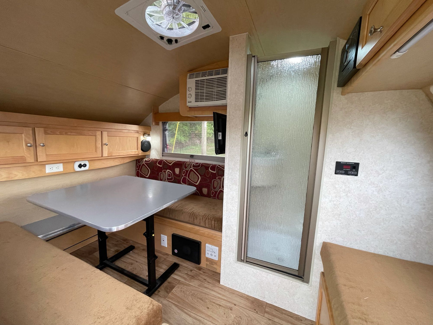 and glowing campfire in a grassy field at sunset.|This compact RV rental teardrop camper features an open rear kitchen with a stove