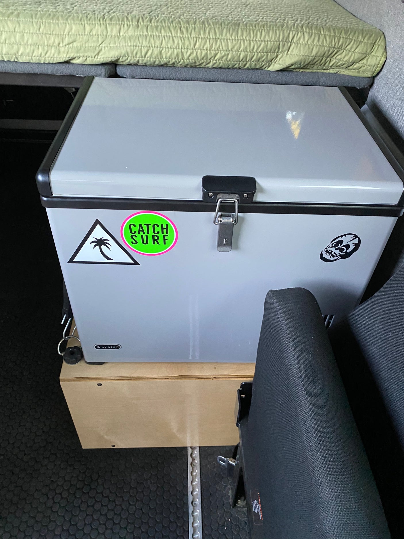 Whynter portable fridge in an RV rental van. Sits on a wooden box, under a bed, great for adventure trips.