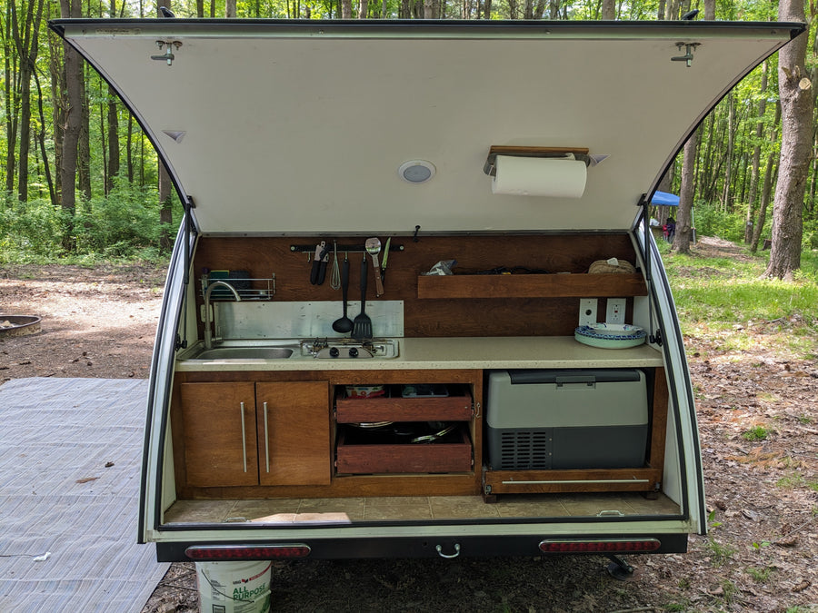 and lower textured trim.|Compact RV rental kitchen with stainless steel sink