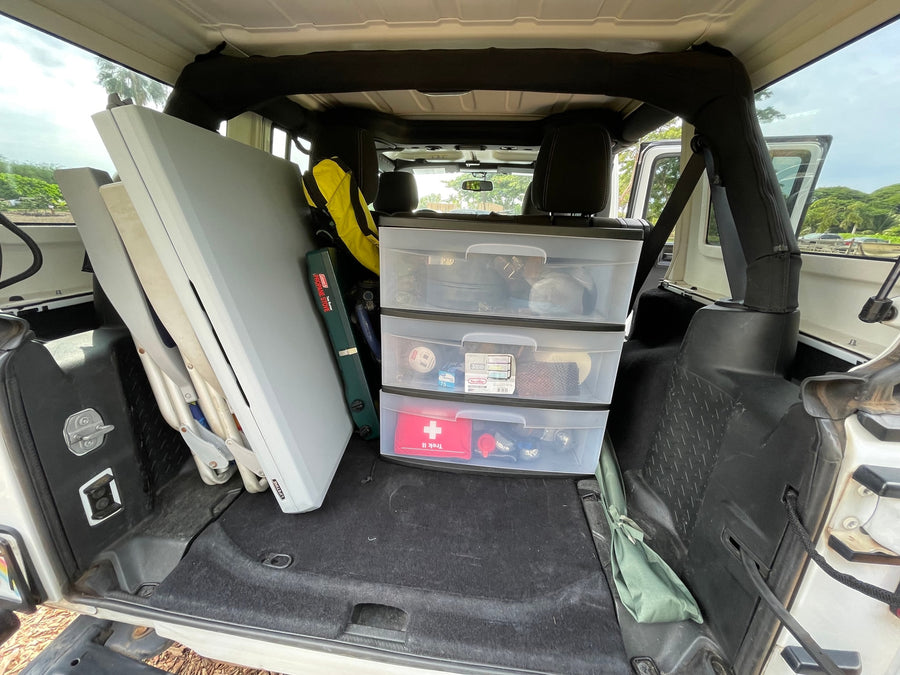 Back of a Jeep filled with camping essentials: stove, tables, & organized storage. Great for an RV rental alternative.