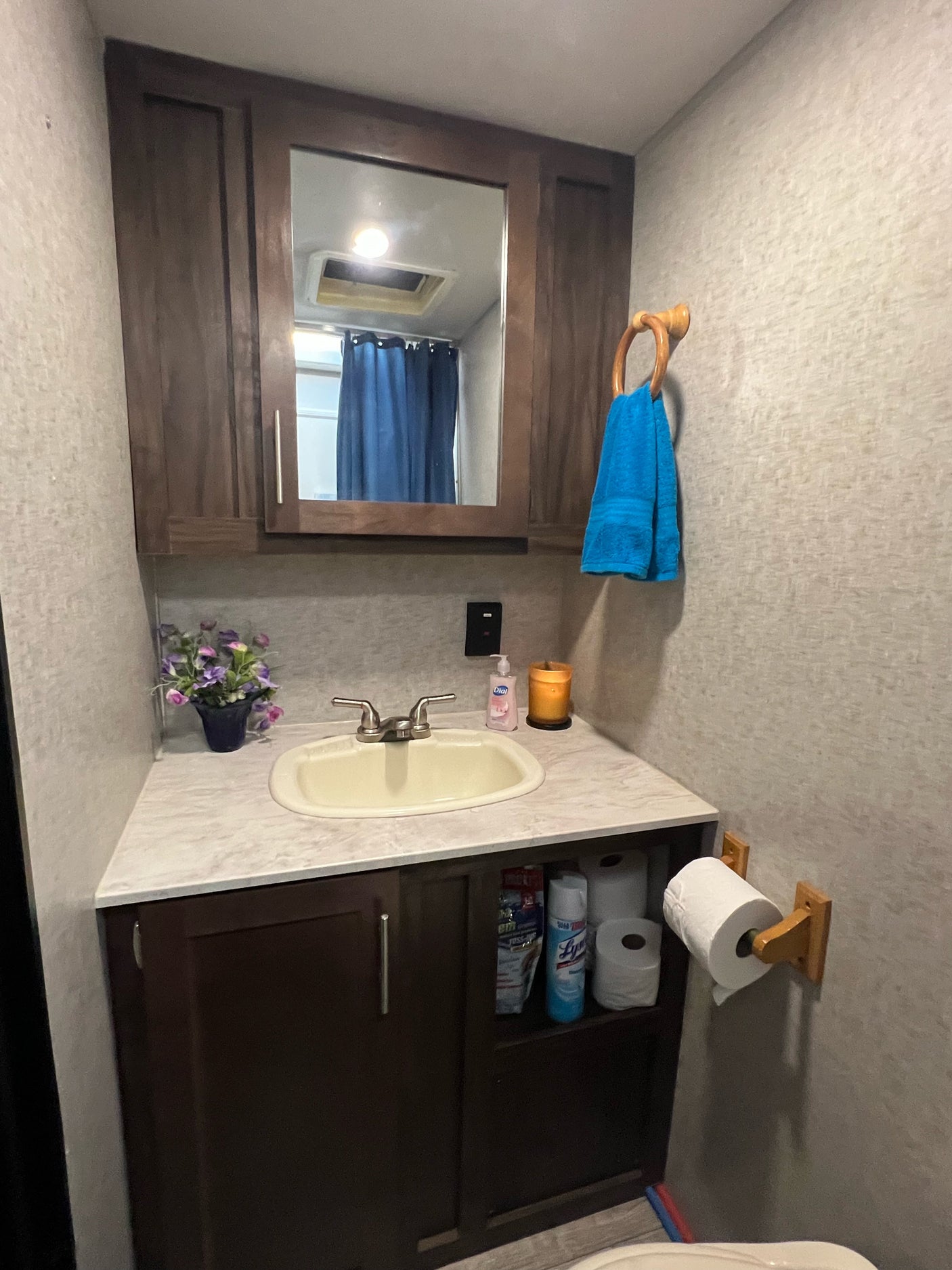 Compact RV rental bathroom with vanity, sink, mirrored cabinet, towel, and storage, perfect for travel.