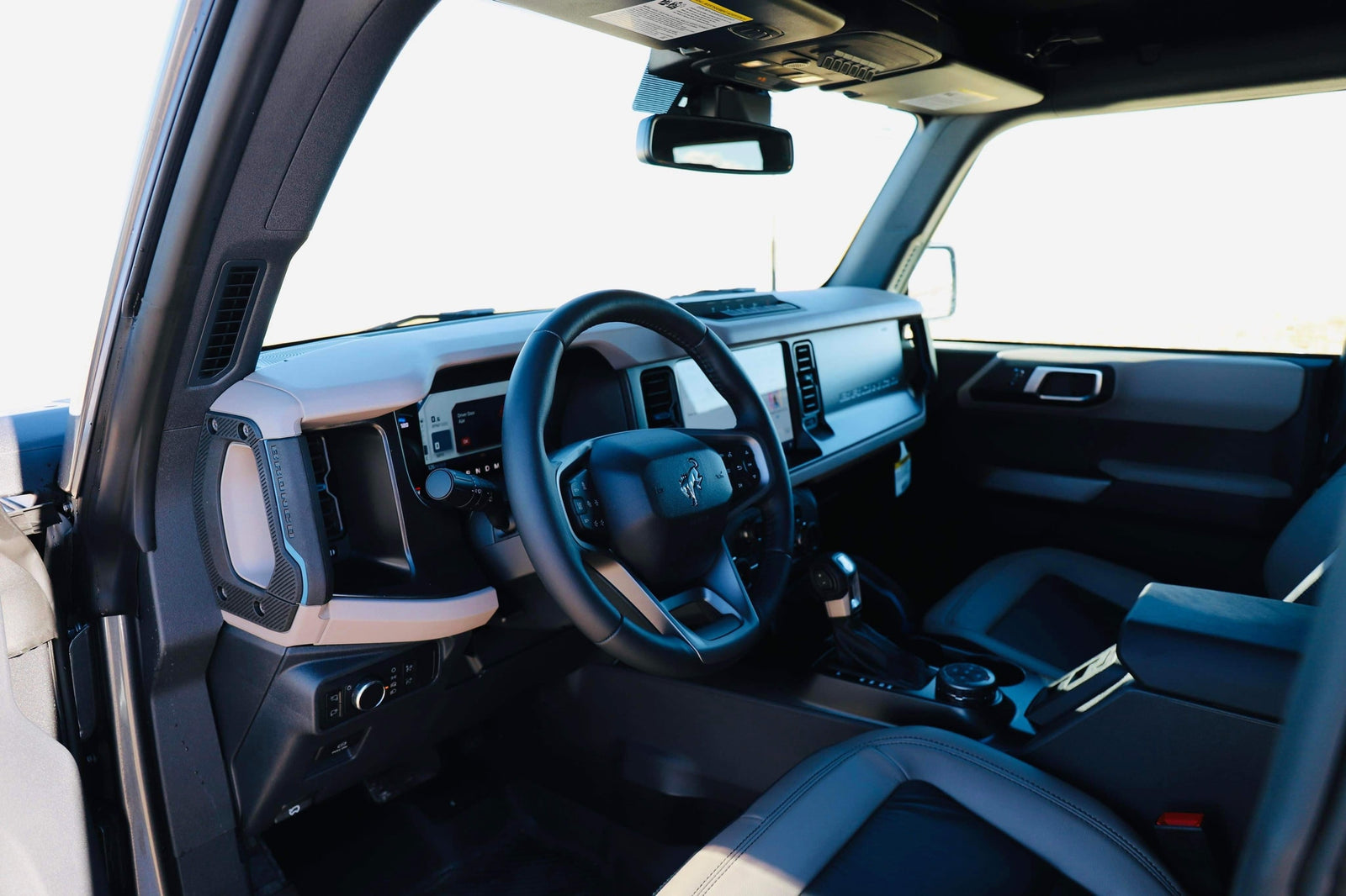 Interior of a Ford Bronco, showcasing its modern dash, steering wheel, and seats. A great option for adventures, even without an RV rental.