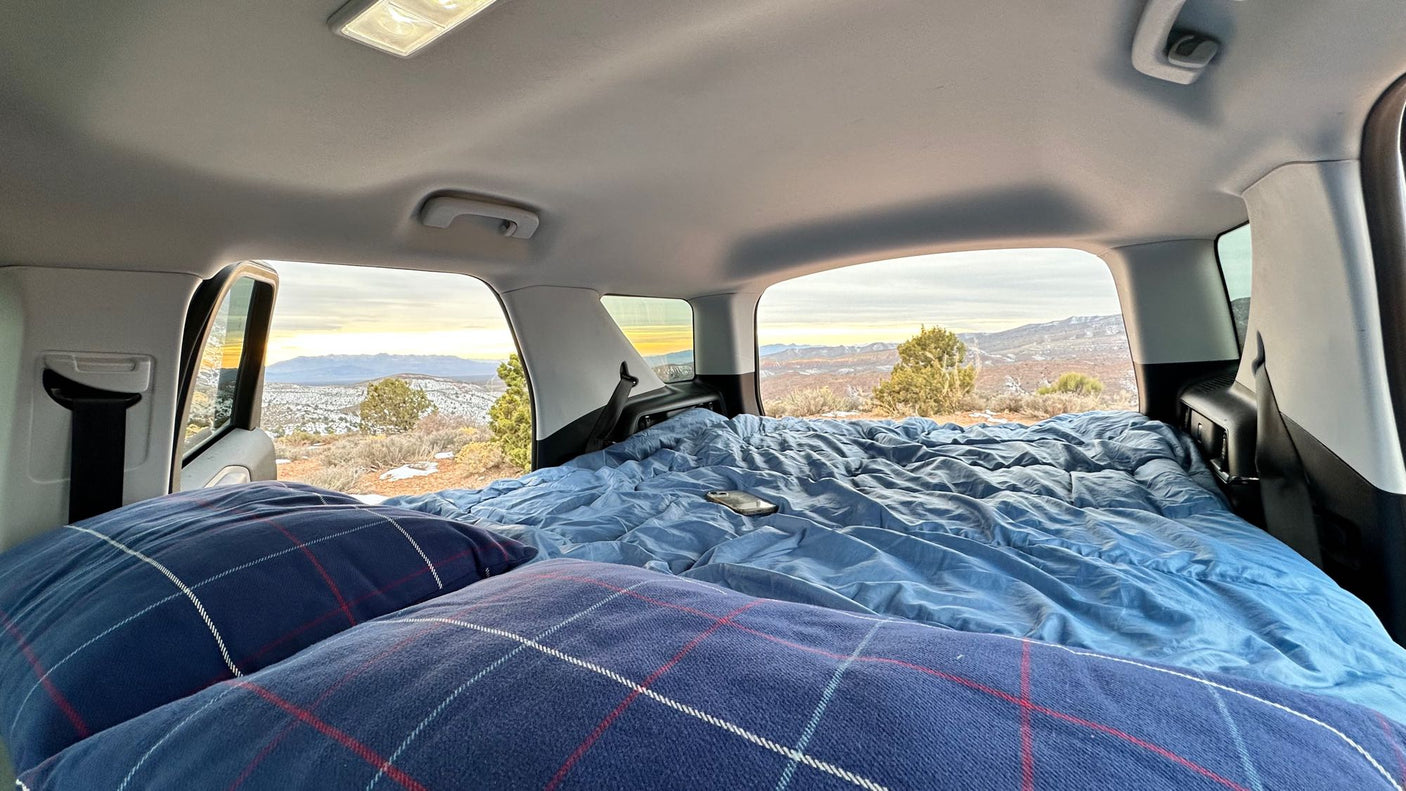 like an RV rental experience.|Interior of a parked vehicle with a cozy bed. Outside