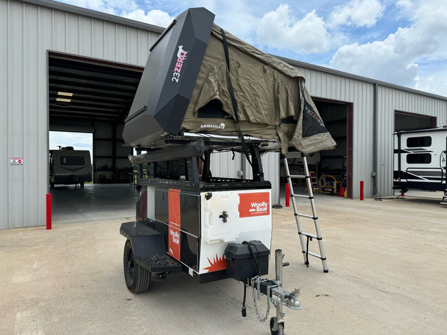 A robust off-road camping trailer, the Woolly Bear, with a 23ZERO rooftop tent, ideal for your next RV rental adventure.