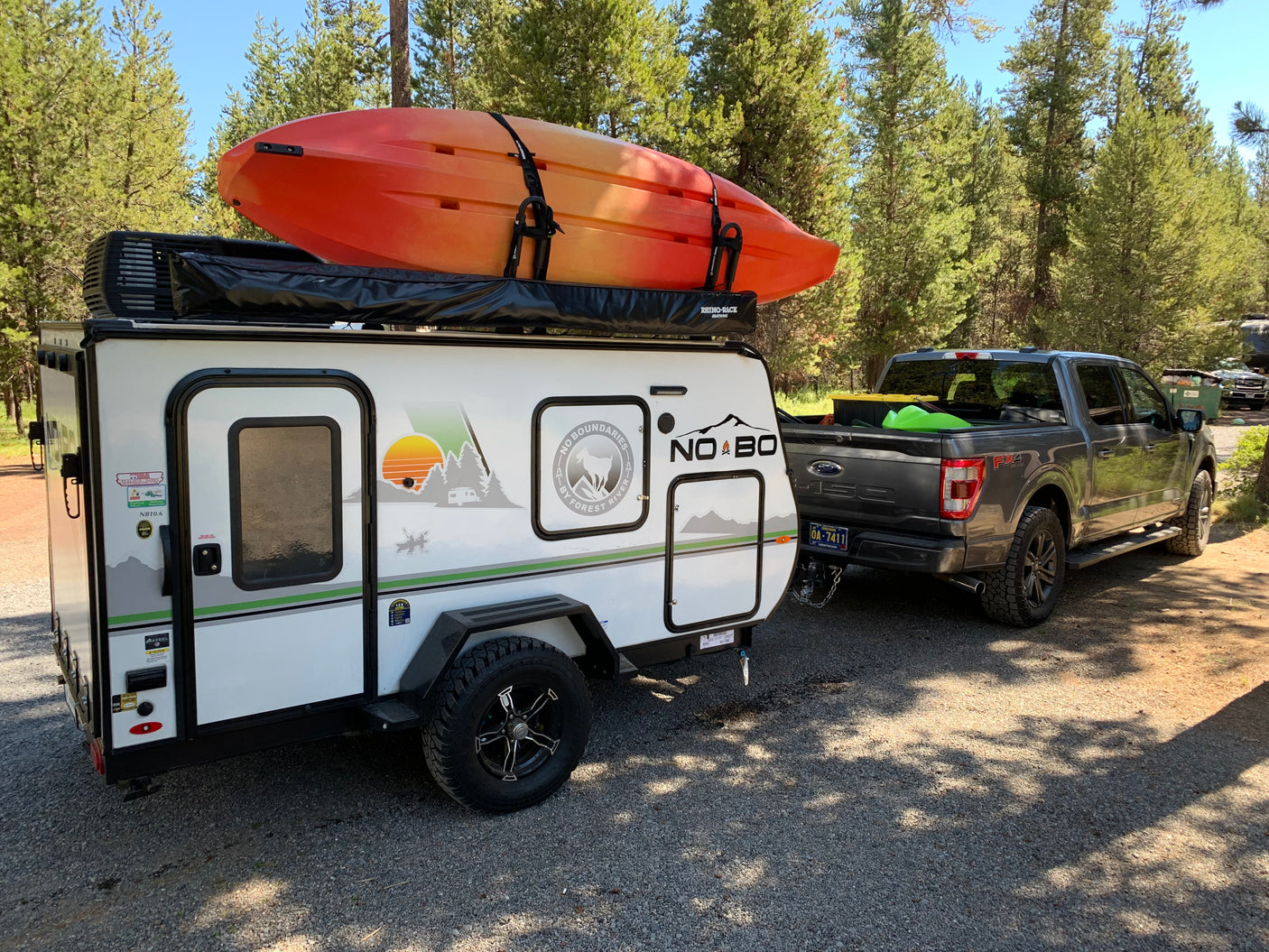RV rental adventure: A No Boundaries travel trailer with a kayak is hitched to a Ford F-150, ready for outdoor fun.