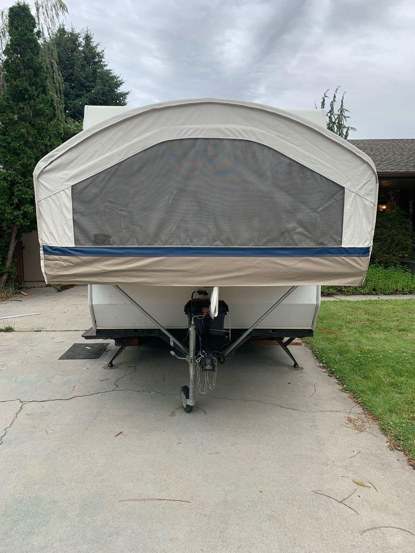 Front of a tan pop-up camper RV rental with a mesh window, parked on a driveway, ready for adventure. — photo 3