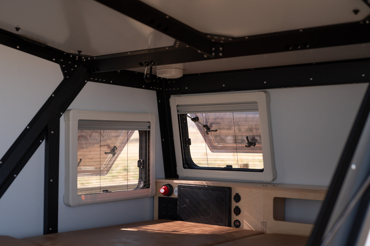 Interior of an RV rental: well-appointed space with large windows, power hub, and comfy sleeping area.
