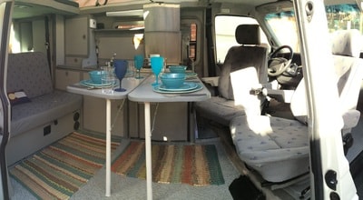 Spacious RV rental interior featuring a set dining table and comfortable seating. Ready for your road trip adventure.