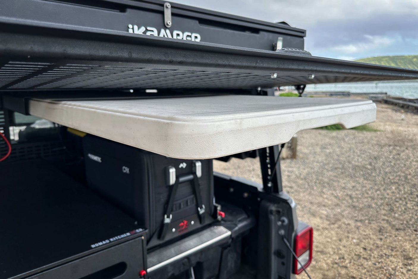 This RV rental setup features a rooftop tent, pull-out table, fridge, and kitchen system for vehicle camping.