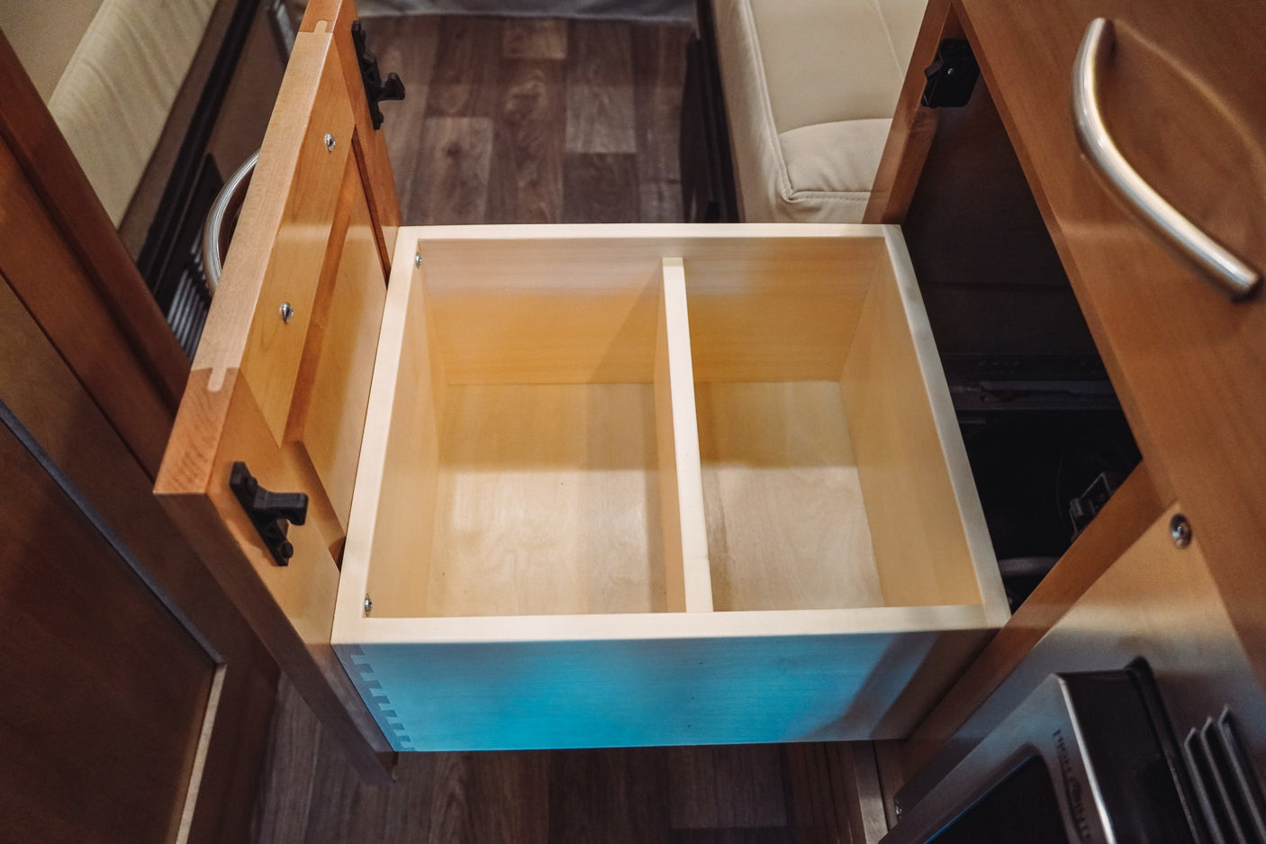 Organized storage in your RV rental! An empty, divided wooden drawer is ready for kitchen essentials in this cozy camper.