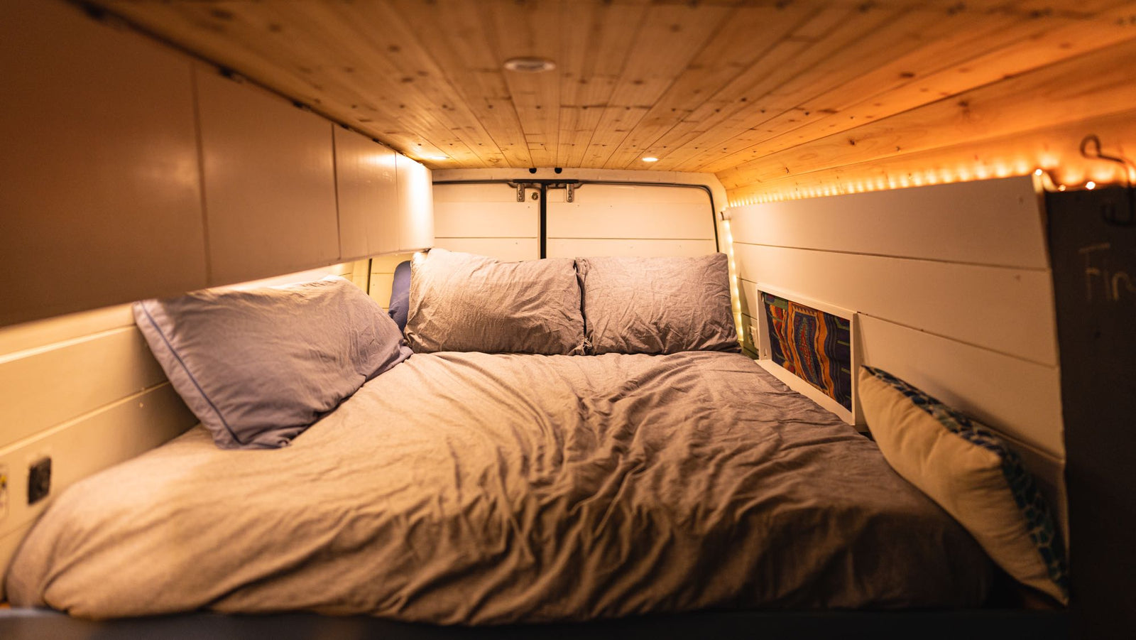 with a digital temp gauge & nearby bed.|A white carbon monoxide alarm mounted inside an RV