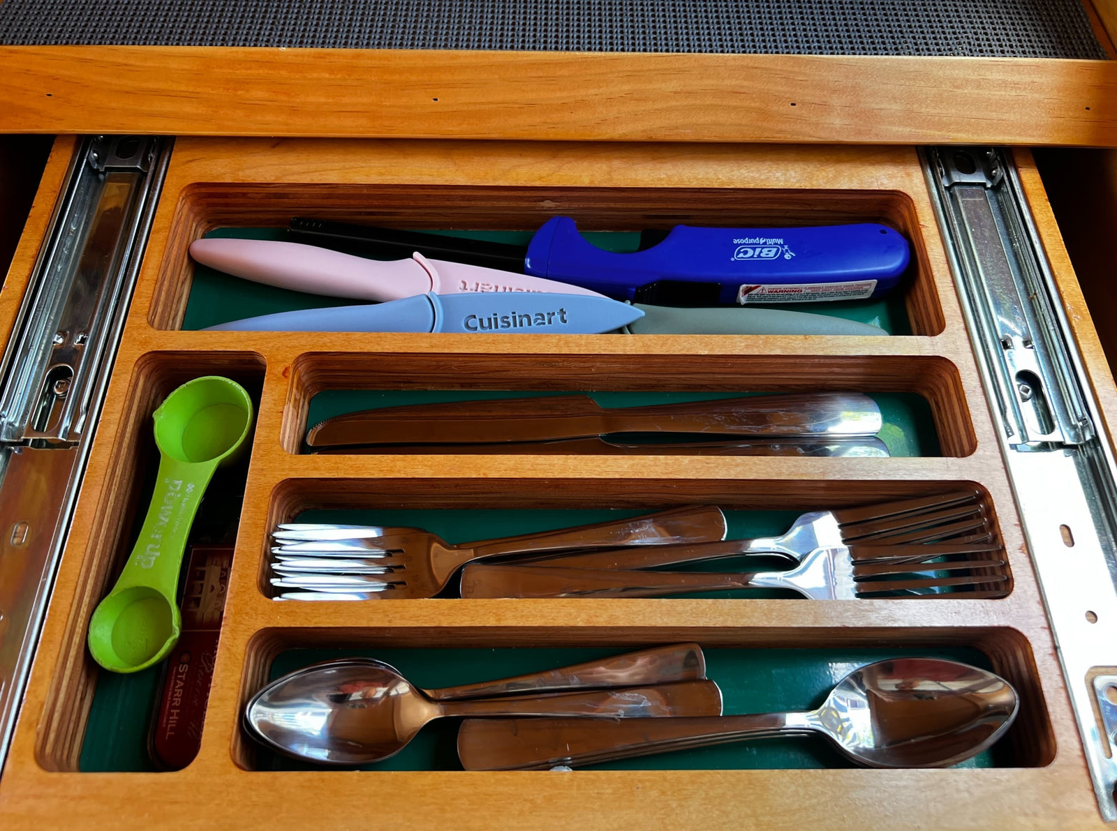 RV rental kitchen drawer. Organized utensils: Cuisinart knives, forks, spoons, measuring spoon, and BIC lighter.