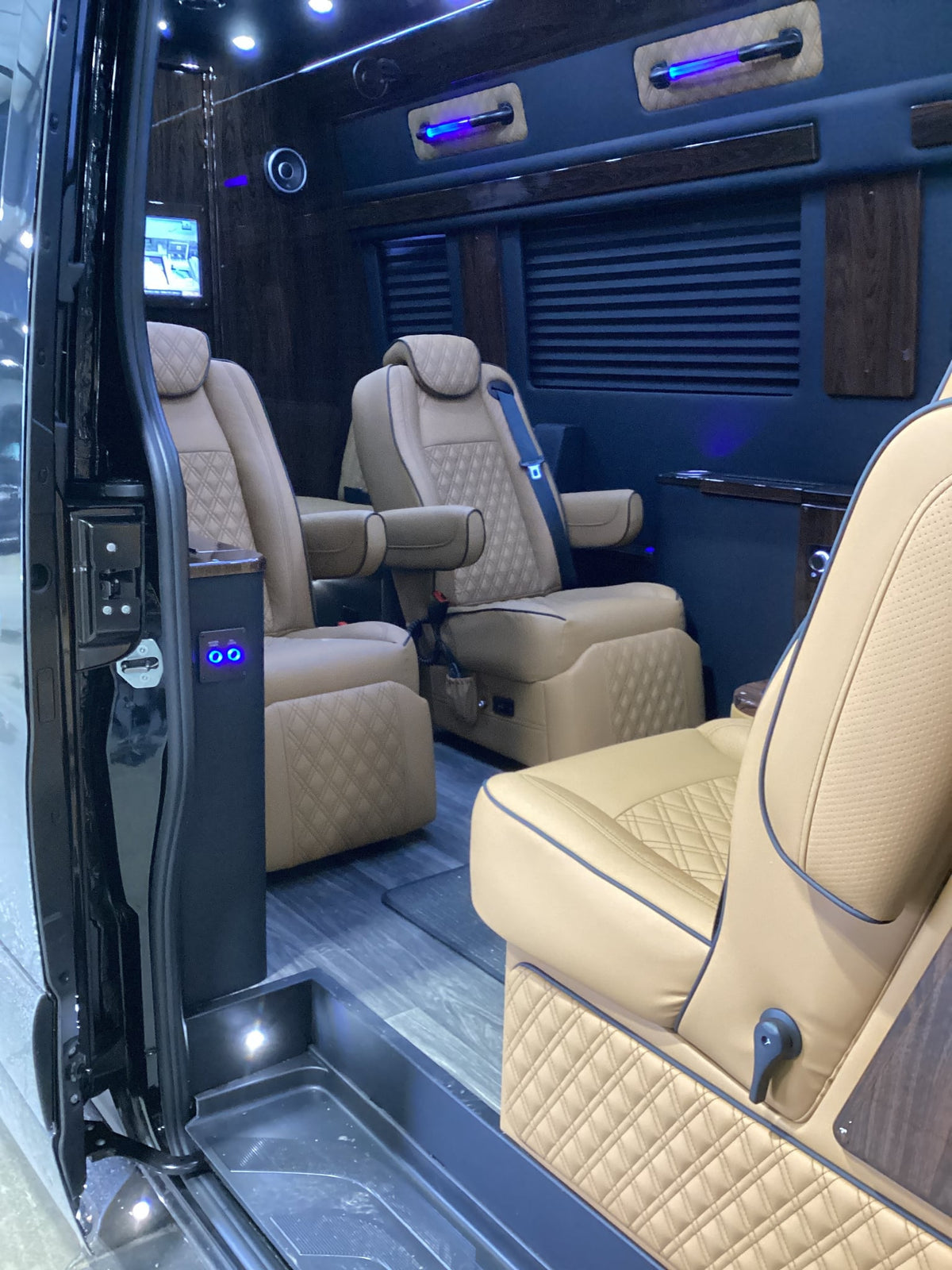 parked on a paved driveway with trees.|Plush tan leather captain's chairs in a luxury RV rental — photo 5